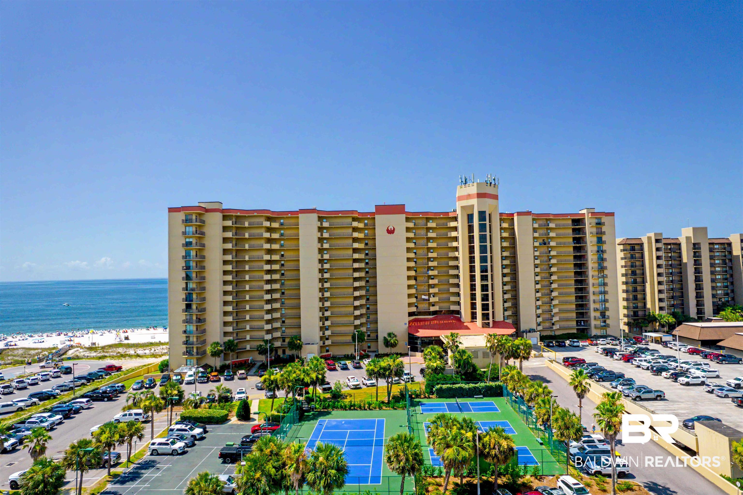 Image 1: Multi-story building directly adjacent to a sandy beach and ocean, featuring numerous private balconies