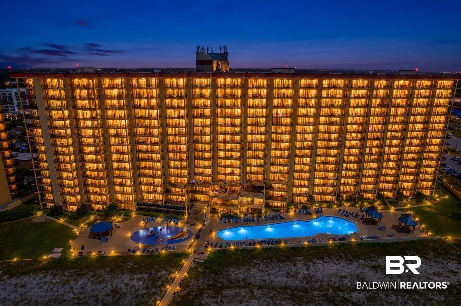 Image 3: Multi-story building featuring illuminated private balconies and a resort-style pool area