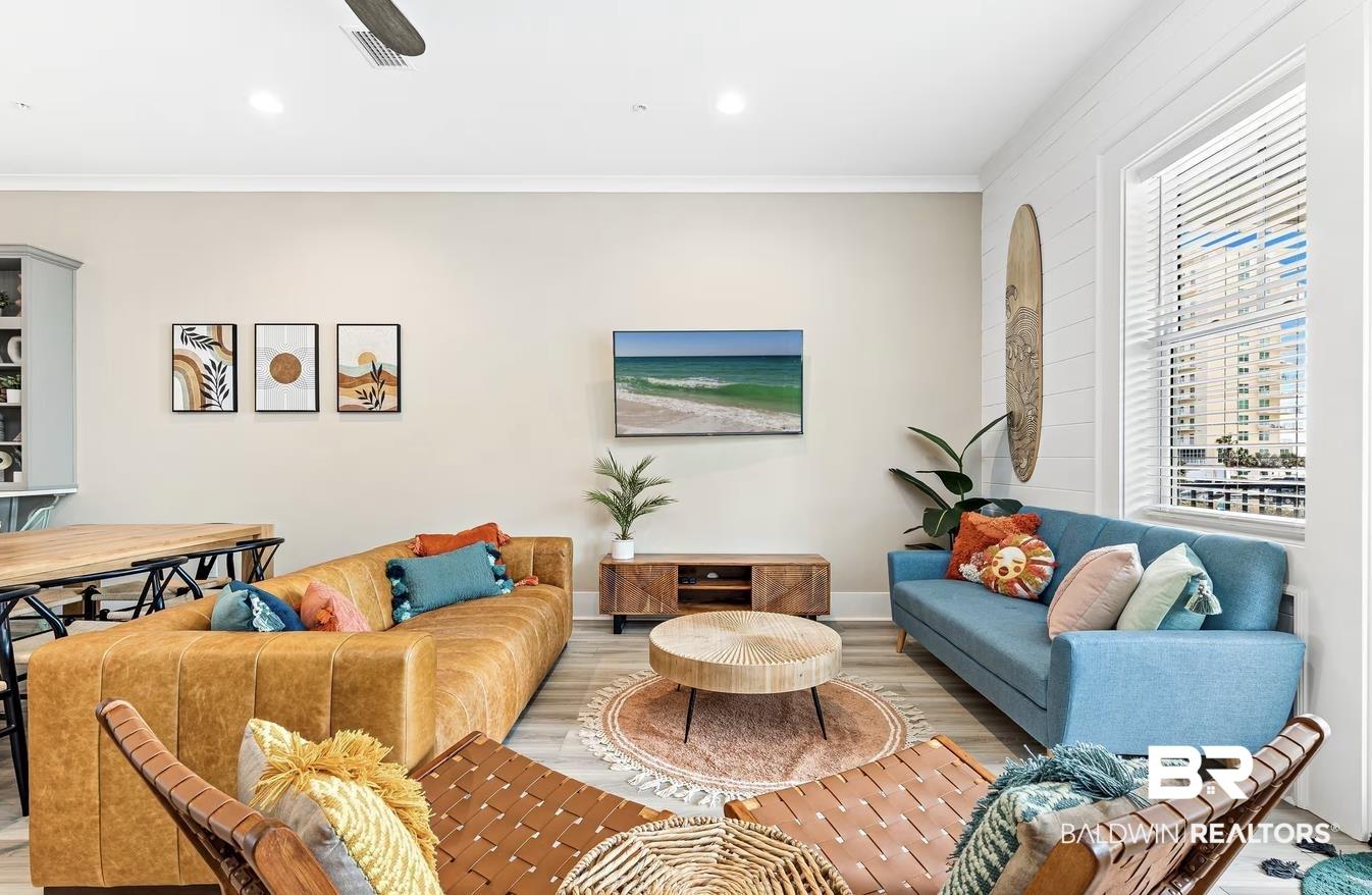 Image 4: Open-concept living area featuring light-toned walls, wood-finish flooring, and a ceiling fan