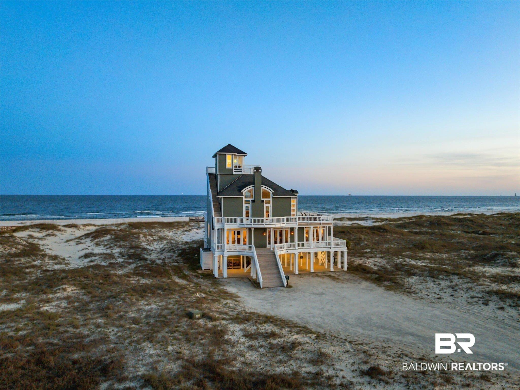 Image 2: Coastal residence featuring multiple levels of outdoor decking, a distinctive cupola, and direct beach access