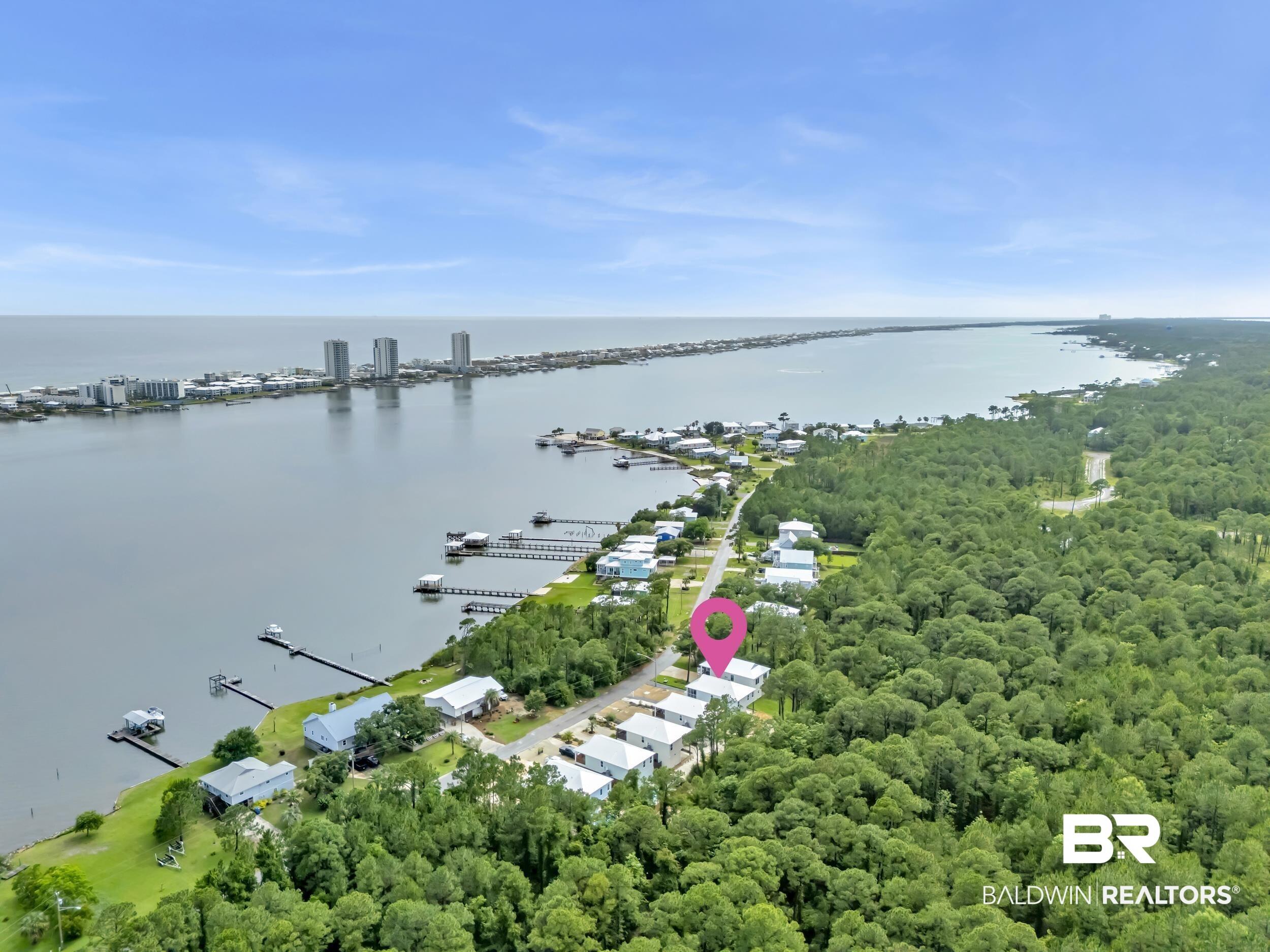Image 2: Aerial perspective showcasing waterfront properties along a tree-lined street