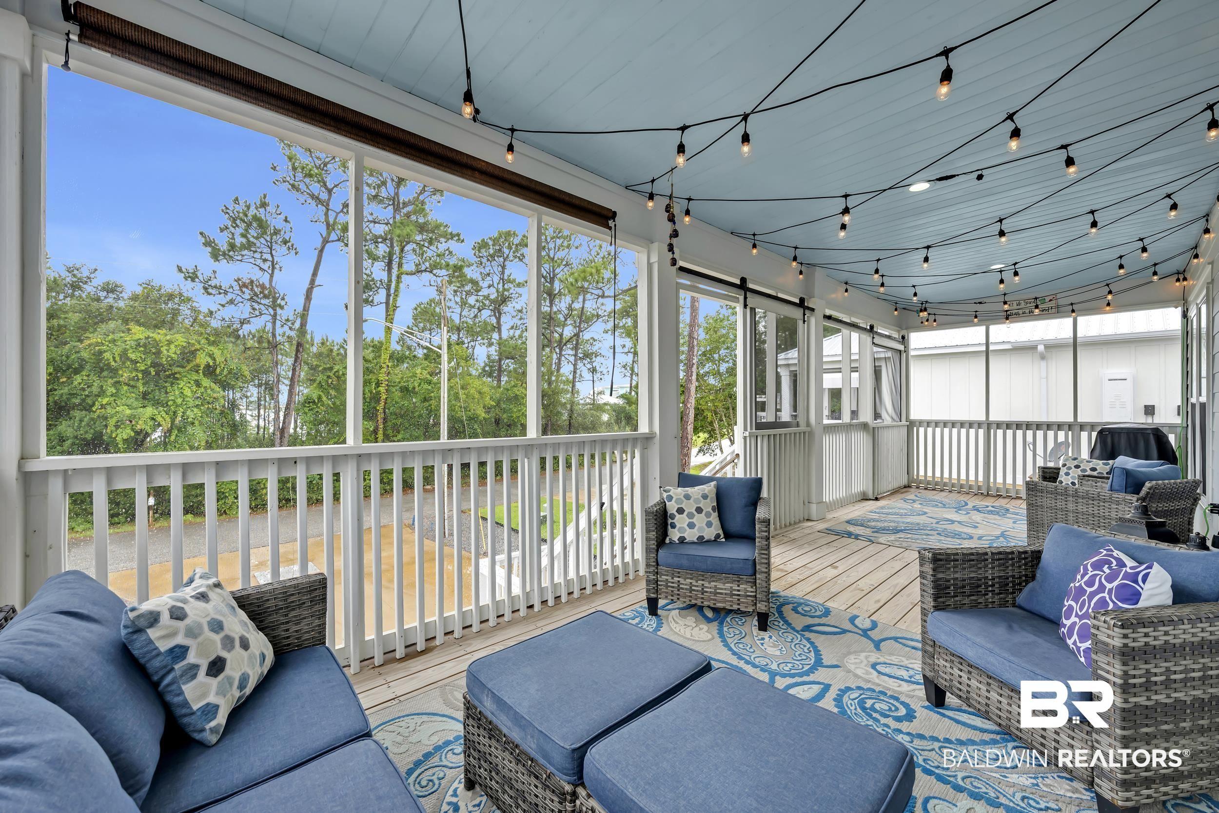 Image 3: Expansive screened porch featuring a light blue ceiling, string lighting, wood-finish flooring, and white railing