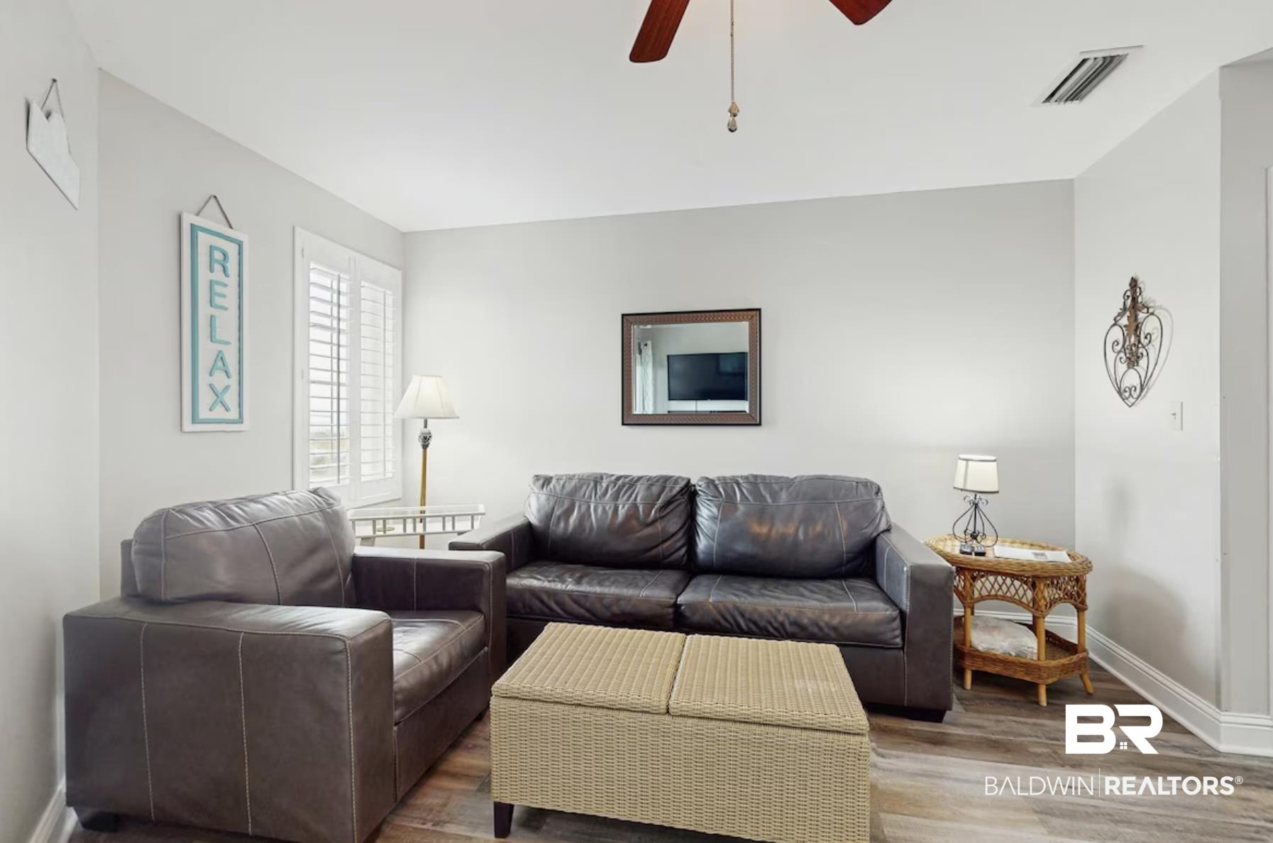 Image 3: Inviting living area featuring wood-finish flooring, plantation shutters, and a ceiling fan