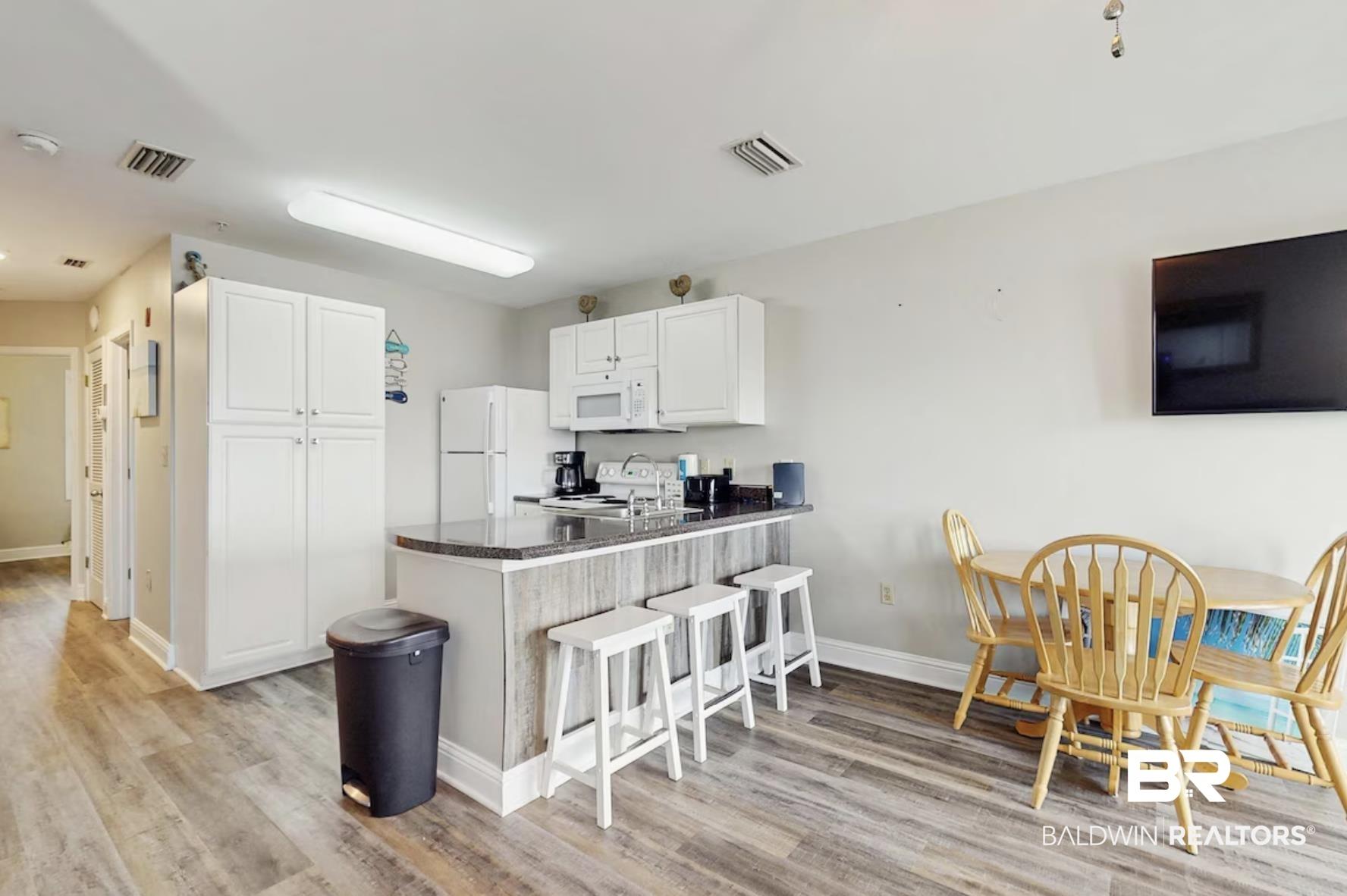 Image 4: Open-concept kitchen and dining area featuring wood-finish flooring