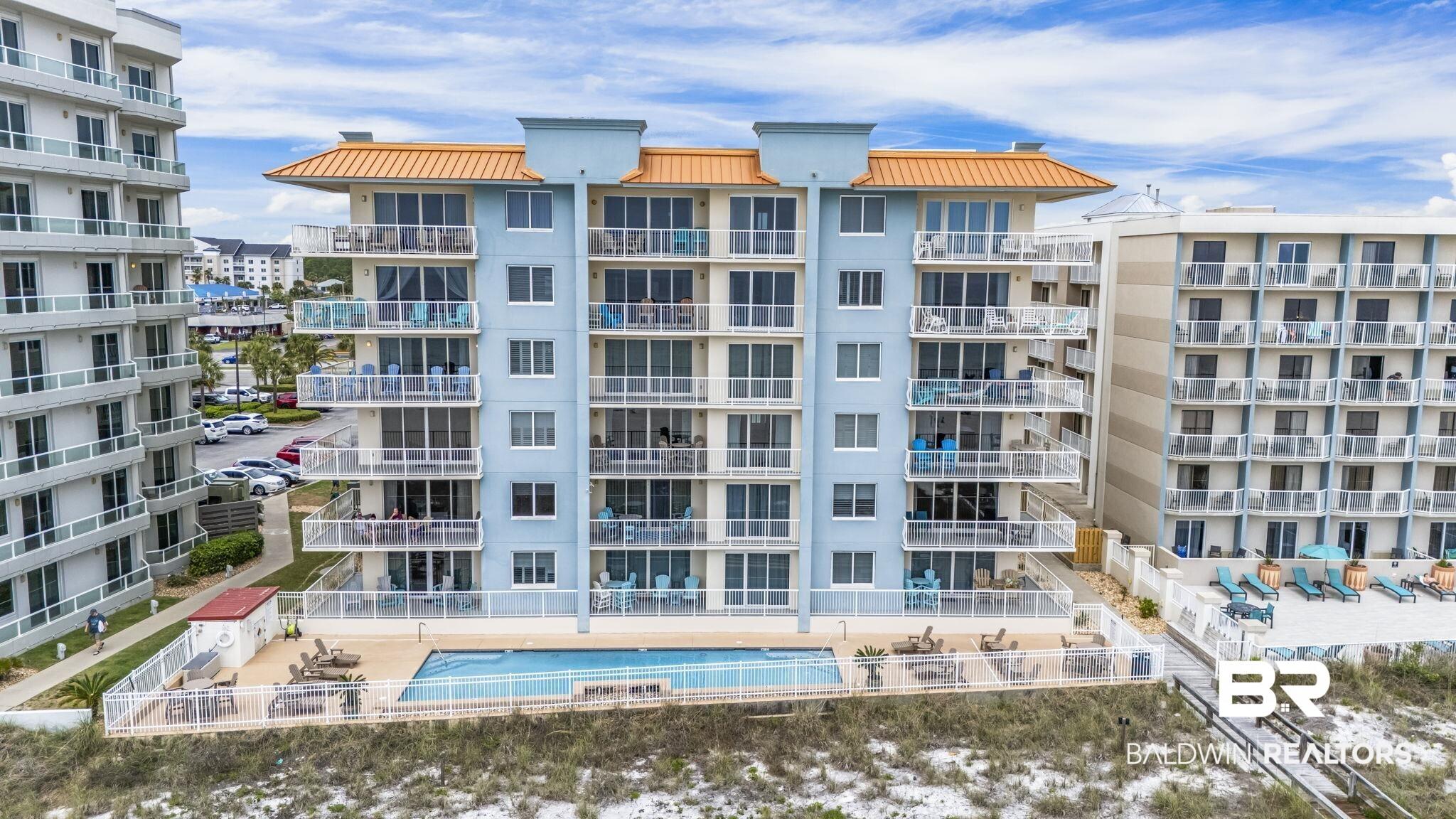 Image 2: Multi-story condominium building featuring a light blue exterior and orange-hued roof