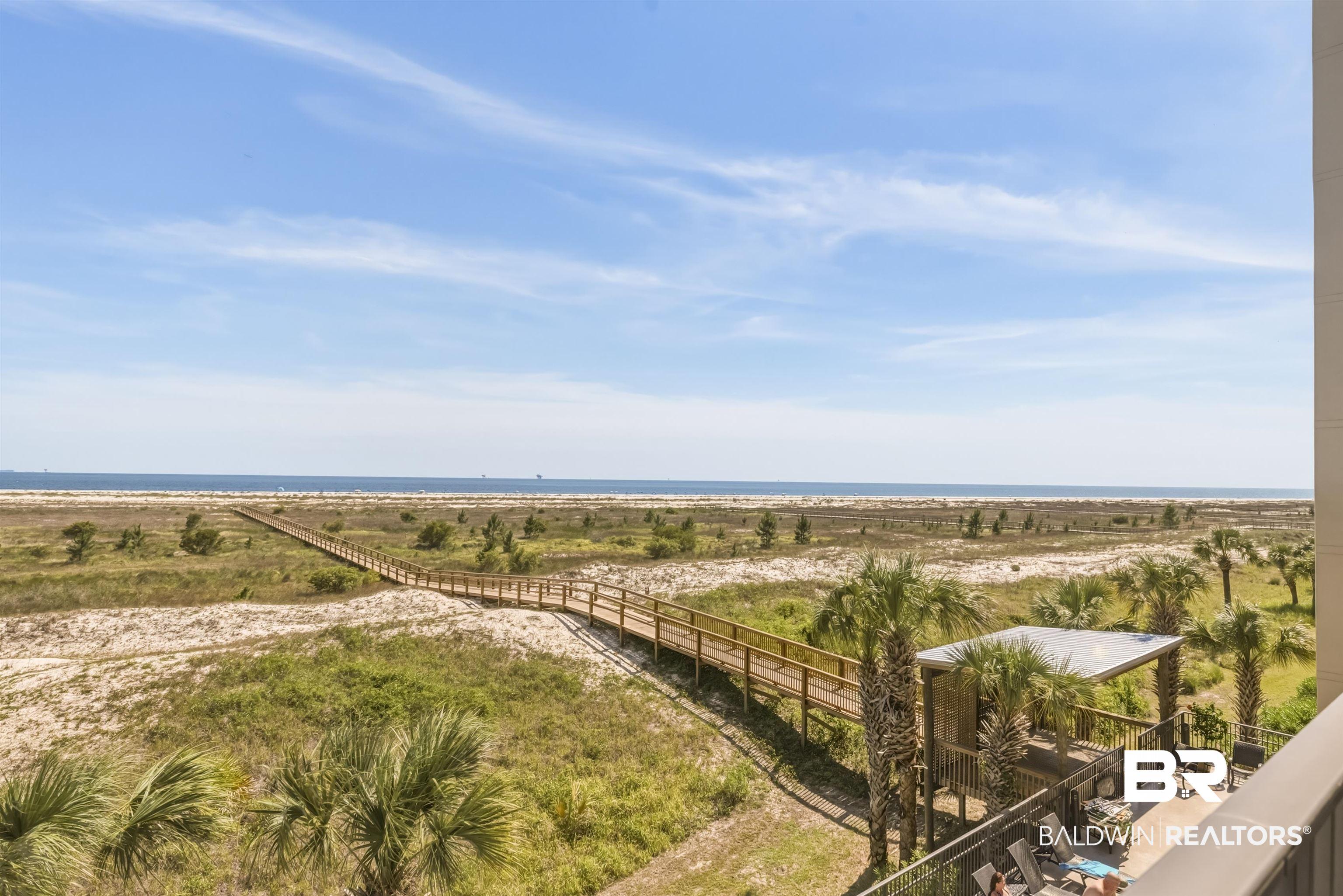 Image 3: Expansive coastal landscape featuring a boardwalk extending towards the water, natural dunes, and mature palm trees
