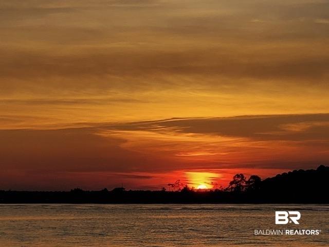 Image 3: Expansive water frontage featuring a vibrant sunset, a silhouetted treeline, and a broad horizon