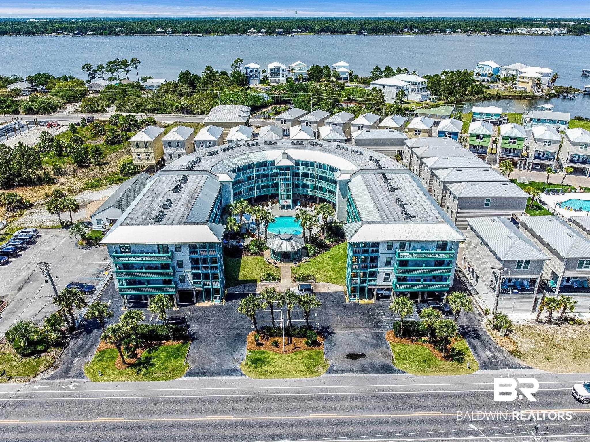 Image 3: U-shaped multi-story condominium building featuring a central swimming pool and surrounding green spaces