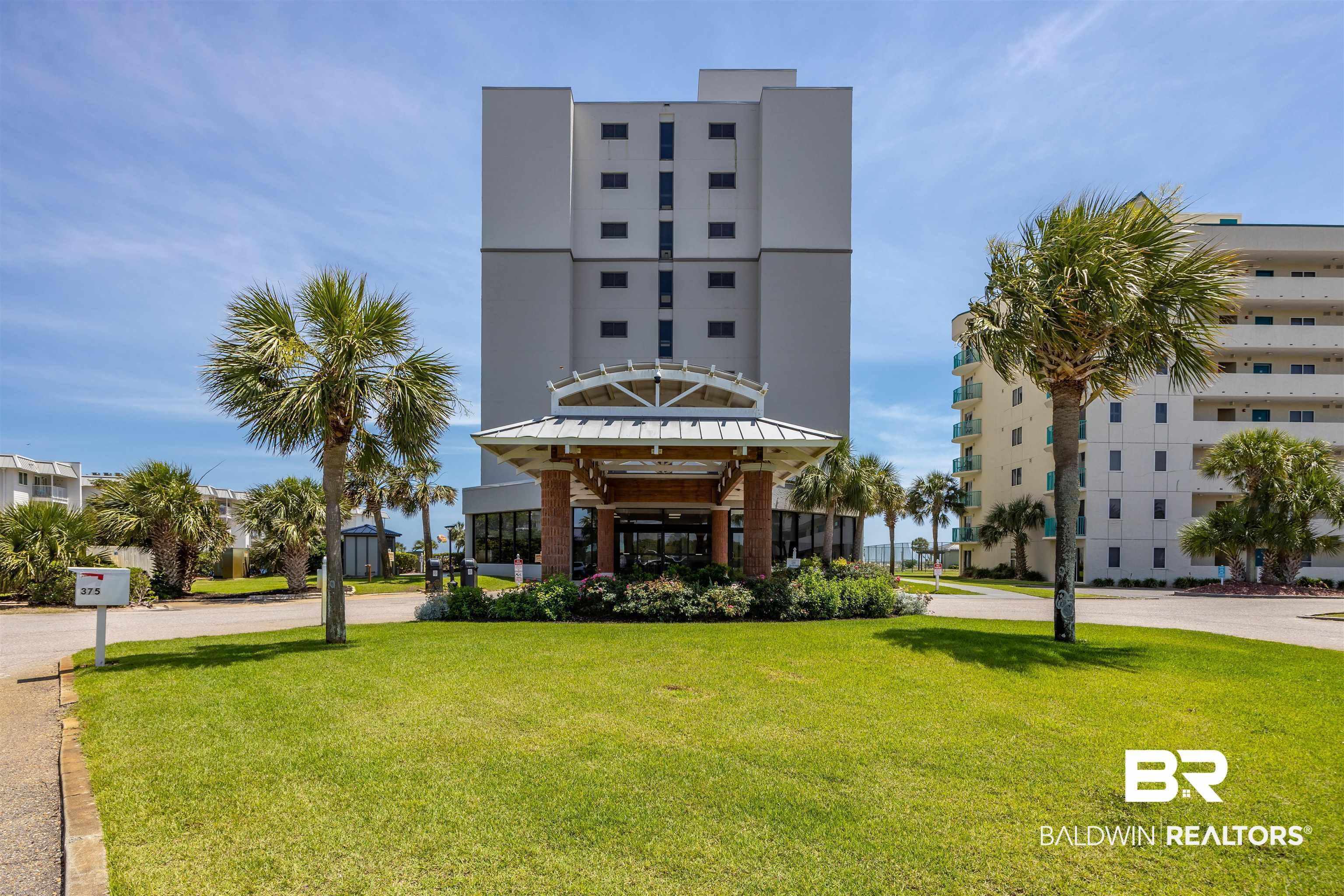 Image 2: High-rise building featuring a covered entrance, contemporary architectural style, and surrounding palm trees