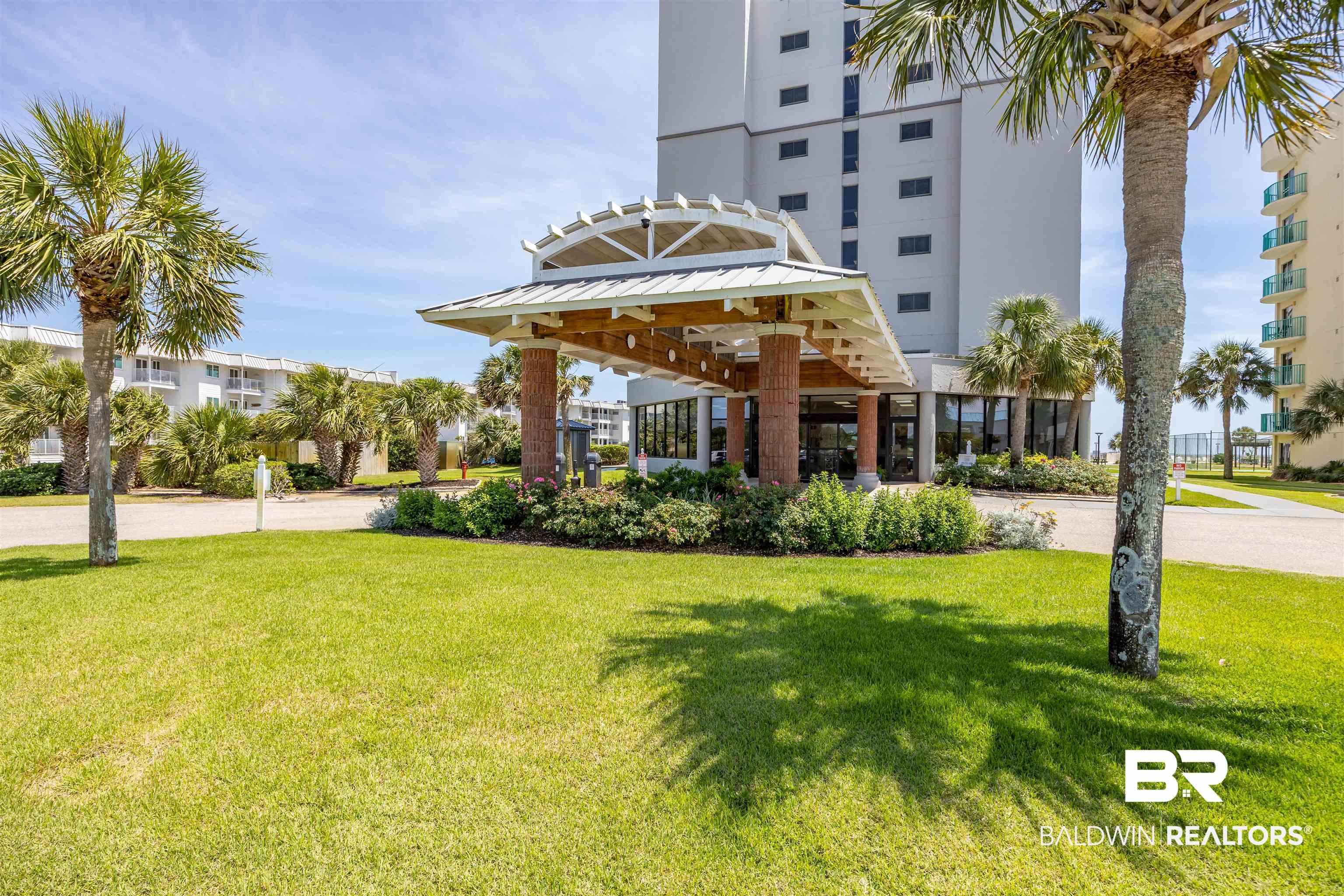 Image 3: Building entrance featuring a covered drive, brick columns, and a landscaped island