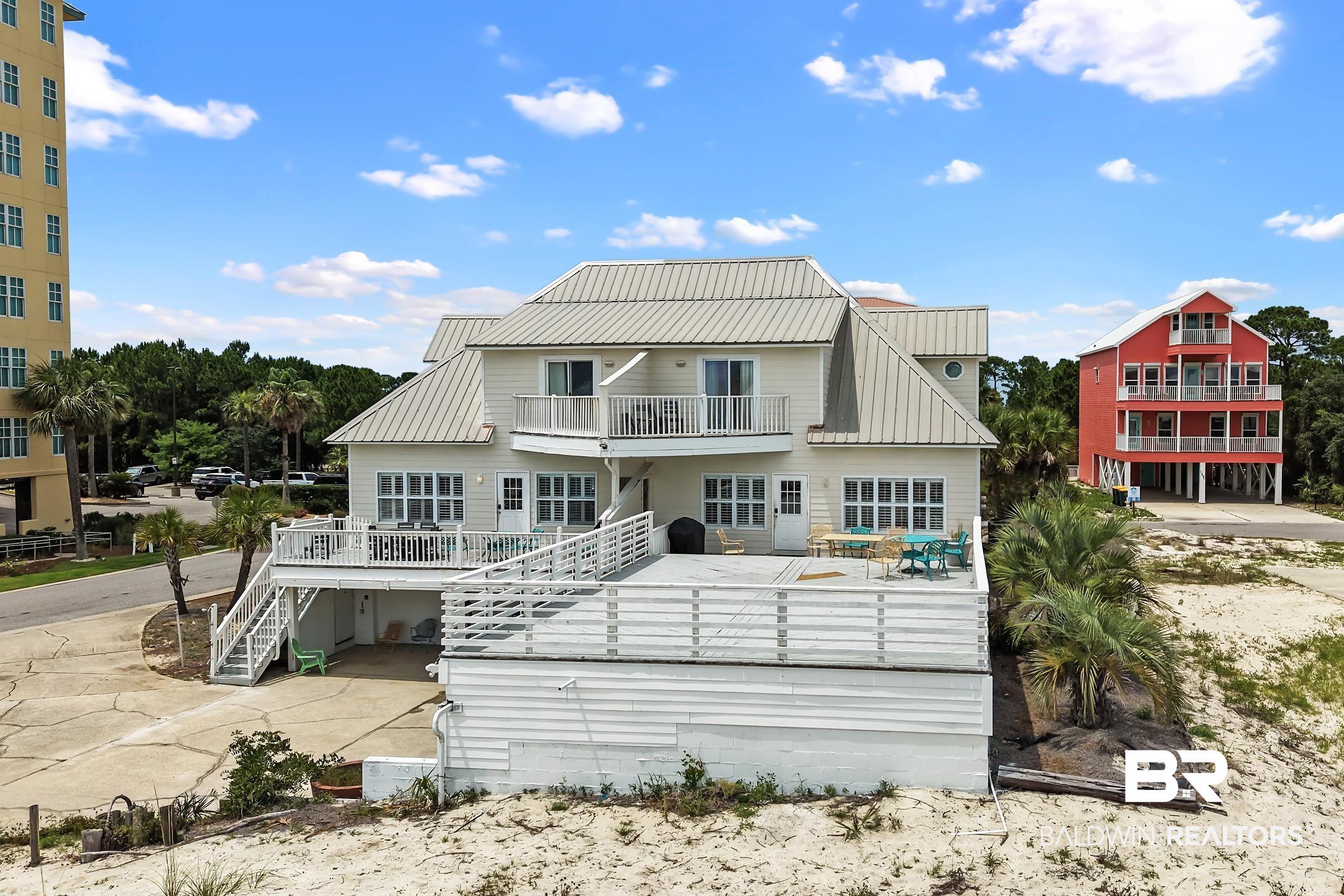 Image 2: Multi-story residence featuring a metal roof, multiple balconies, and an expansive elevated deck