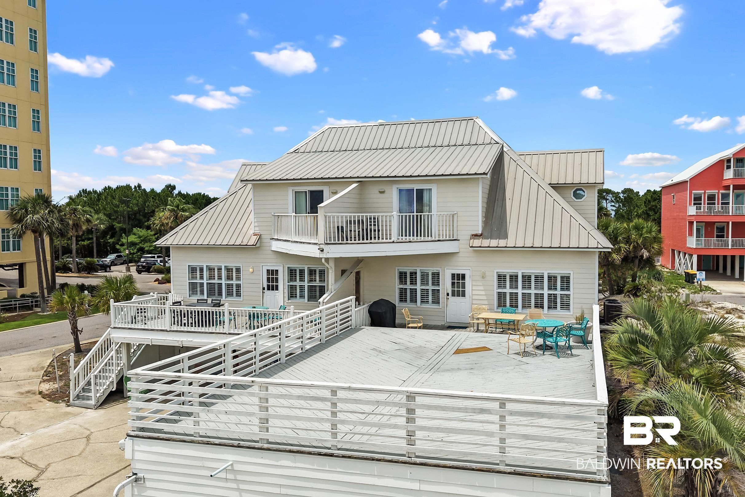 Image 3: Cream-colored exterior featuring a prominent metal roof and multiple windows
