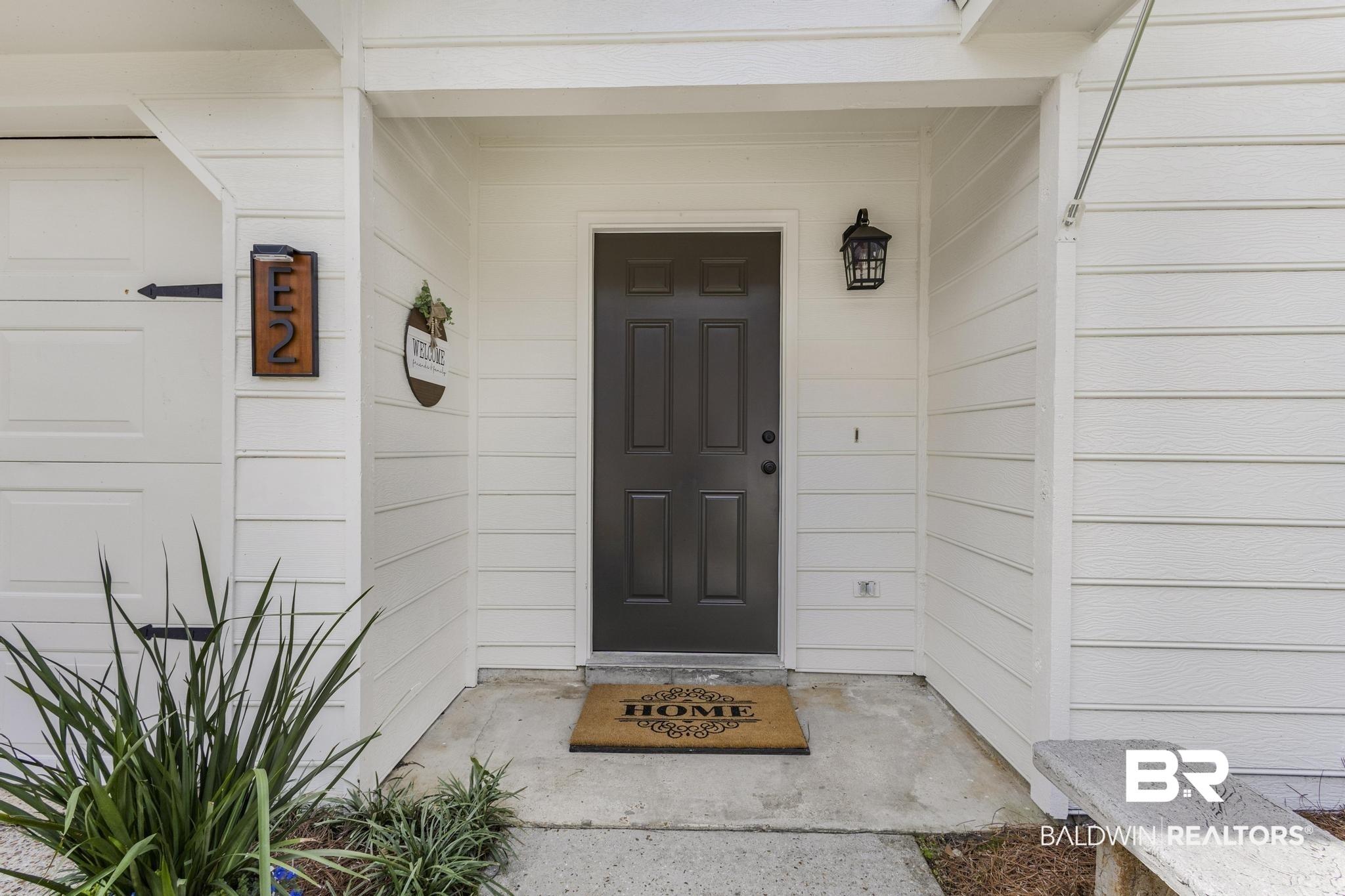 Image 4: Inviting entry with a paneled dark gray door and an exterior lantern light fixture