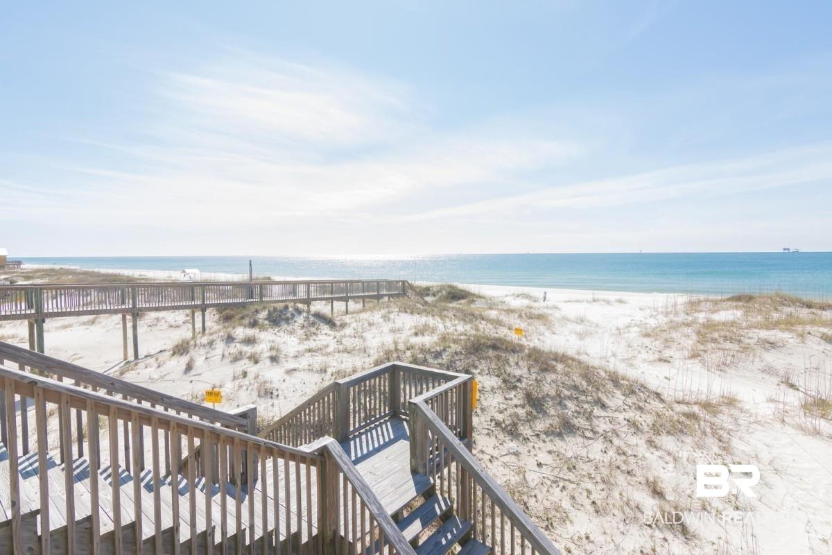 Image 2: Wood-finish boardwalk access to a white sand beach with natural dunes and ocean water