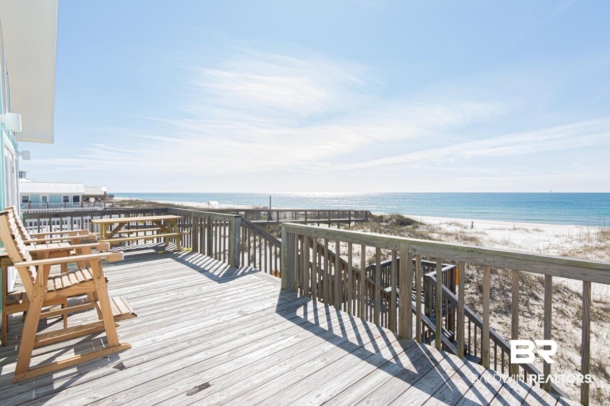 Image 3: Spacious outdoor deck with natural wood flooring and railing, featuring direct access to a white sand beach and expansive ocean