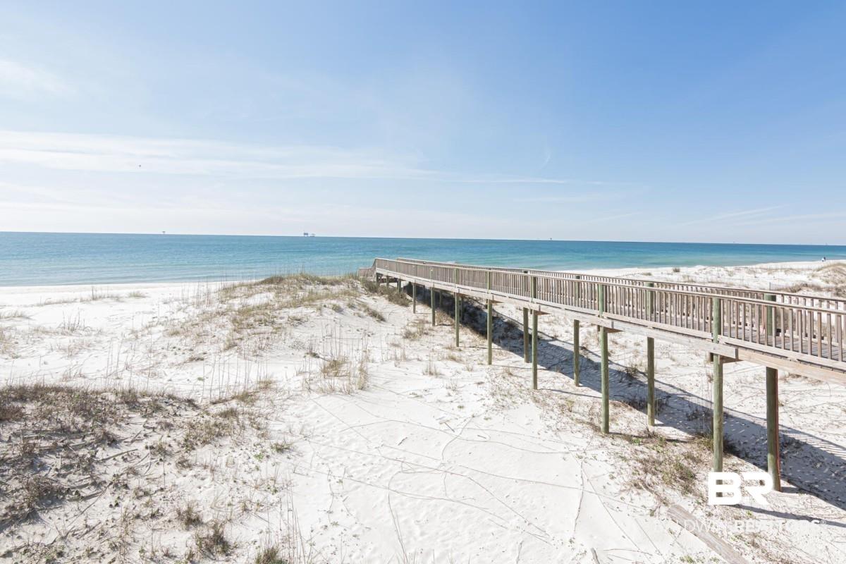 Image 4: Expansive sandy beach with a prominent boardwalk, featuring light-colored sand and dune grasses