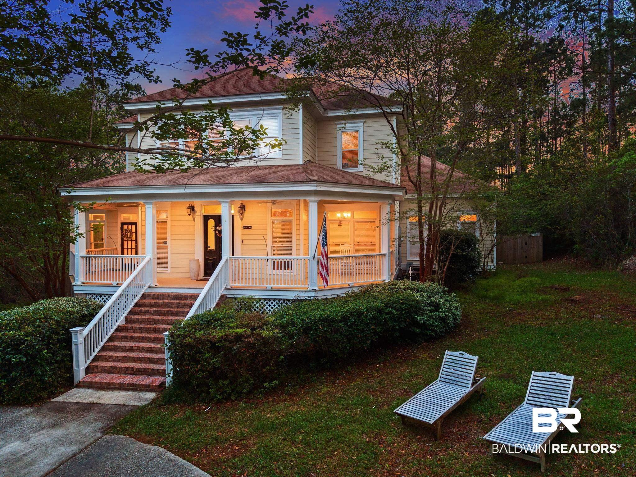 Image 2: Two-story residence featuring a covered front porch with white railings, brick steps, and a dark front door