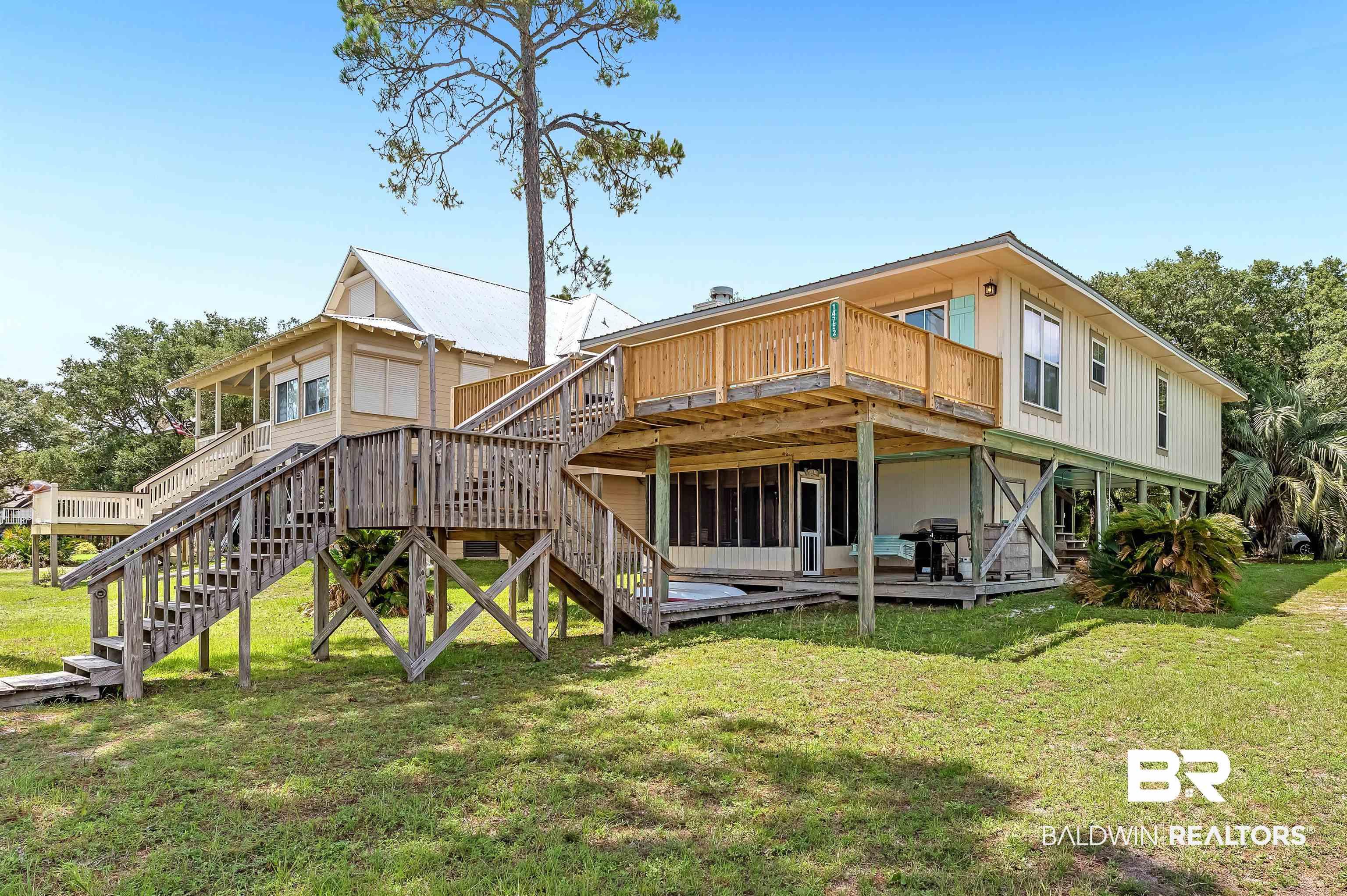 Image 2: Back of house with stairway, a wooden deck, and a lawn