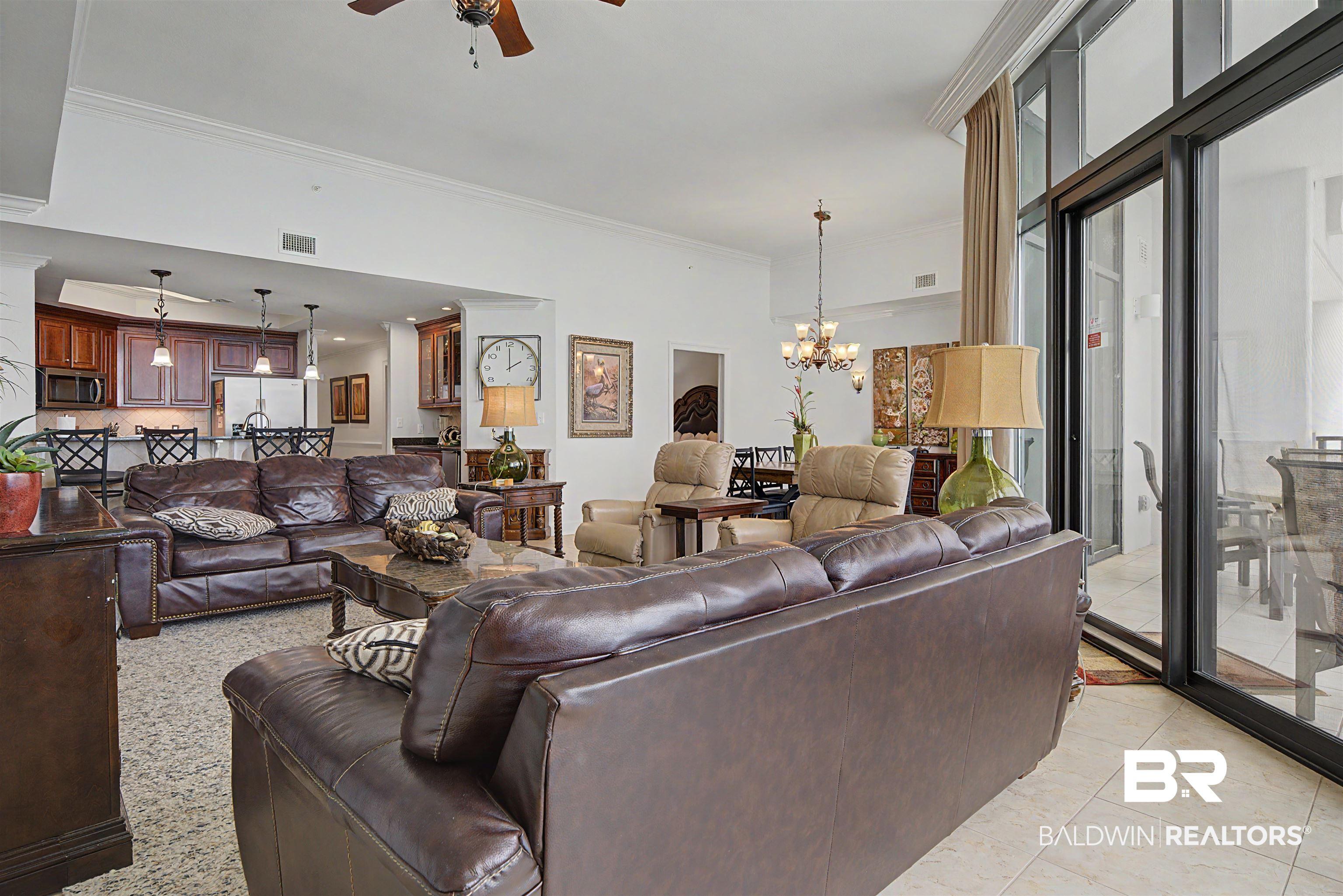 Image 4: Open-concept living area featuring a kitchen with wood cabinetry, a breakfast bar, and pendant lighting