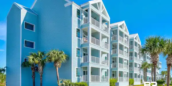 Image 2: Multilevel condominium building featuring light blue siding with white trim