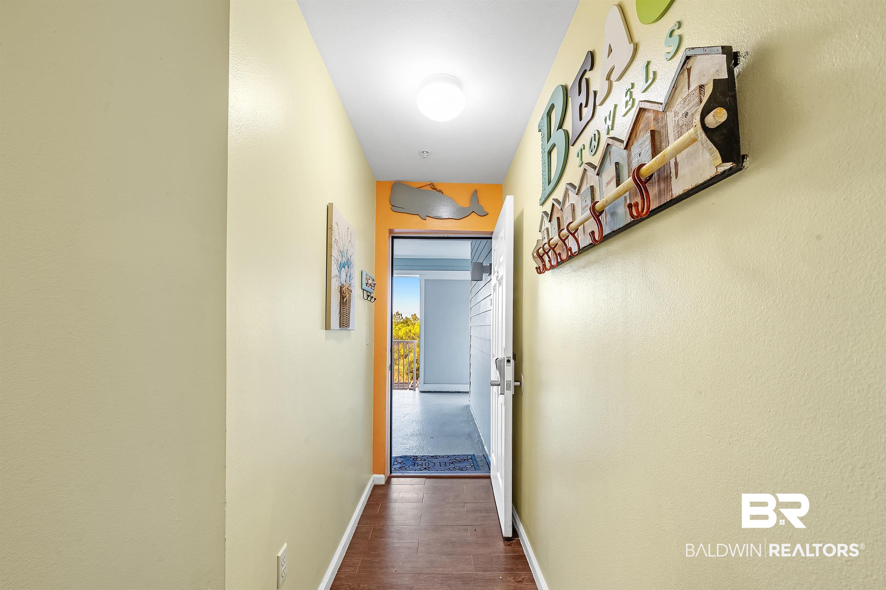 Image 4: Hallway featuring wood-finish flooring, a white door, and light-toned walls