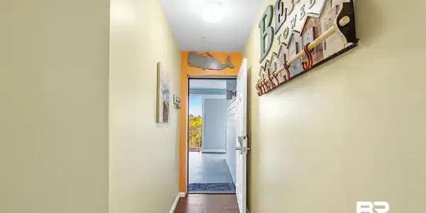 Image 4: Hallway featuring wood-finish flooring, a white door, and light-toned walls