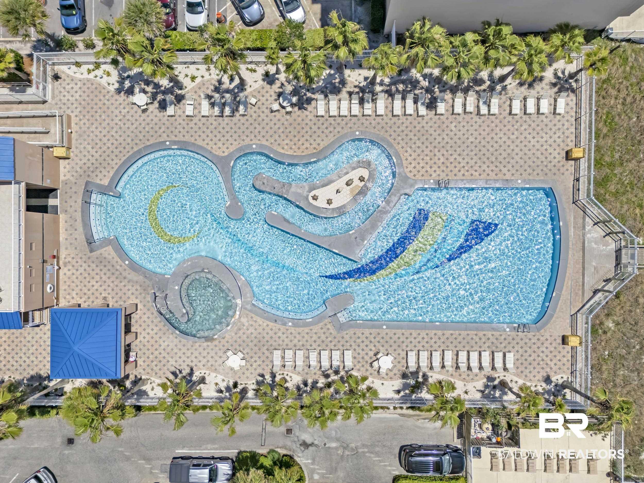 Image 2: Expansive outdoor pool area featuring a freeform pool with integrated mosaic tiling and a connected spa