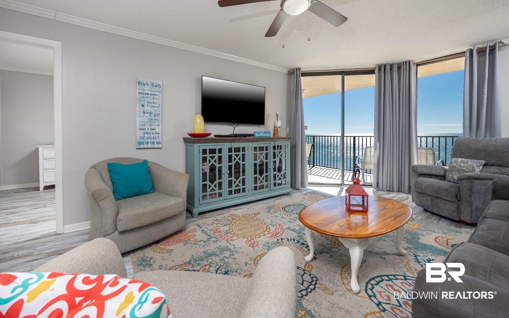 Image 3: Living area featuring full-height sliding glass doors opening to a balcony with water views