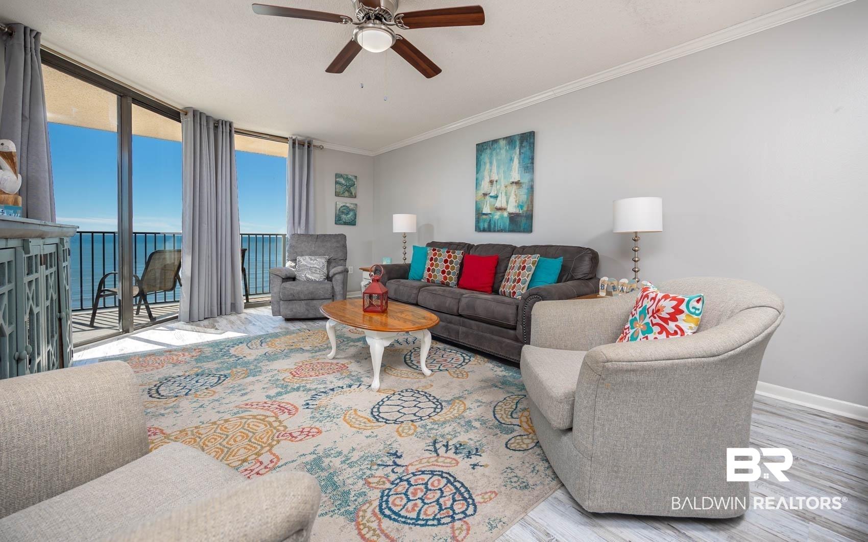 Image 4: Living area featuring expansive floor-to-ceiling sliding glass doors, a ceiling fan, and wood-finish flooring