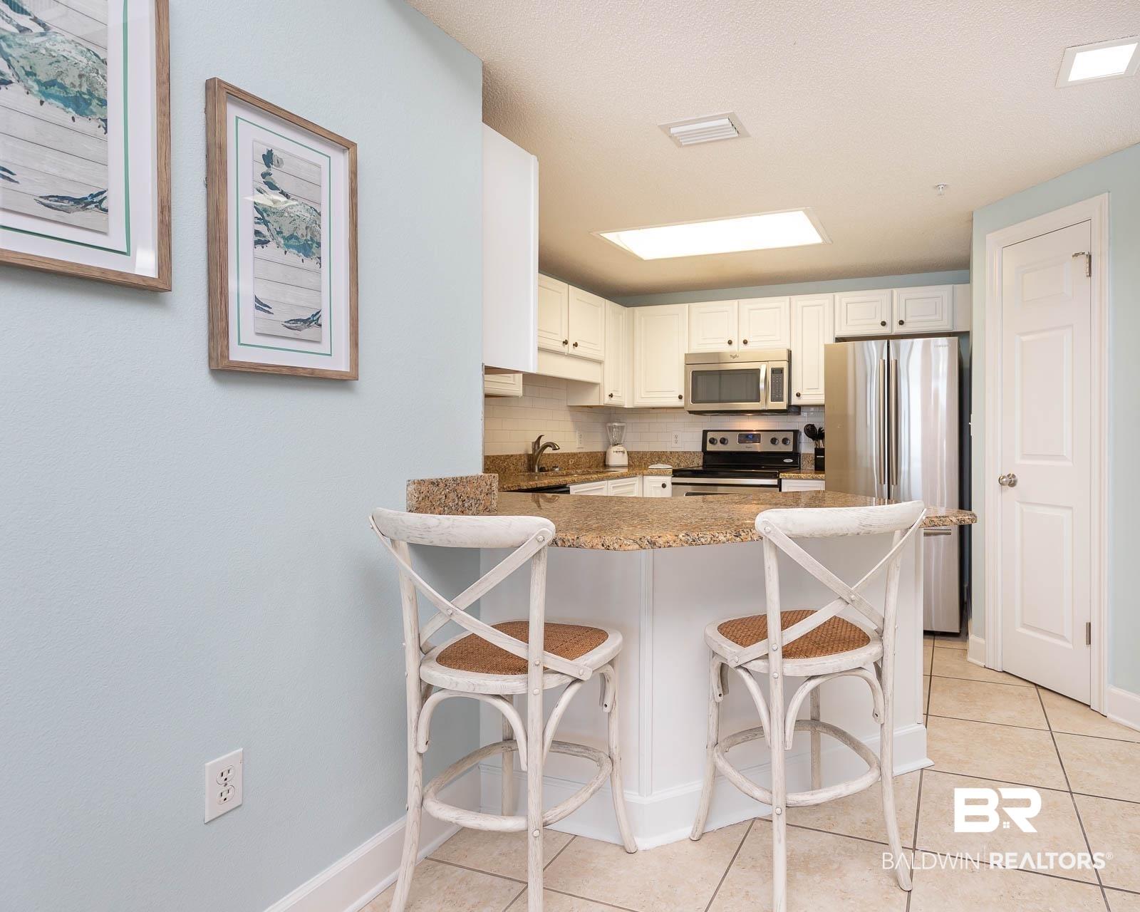 Image 4: Kitchen featuring white cabinetry, stainless steel appliances, granite countertops, and tiled flooring