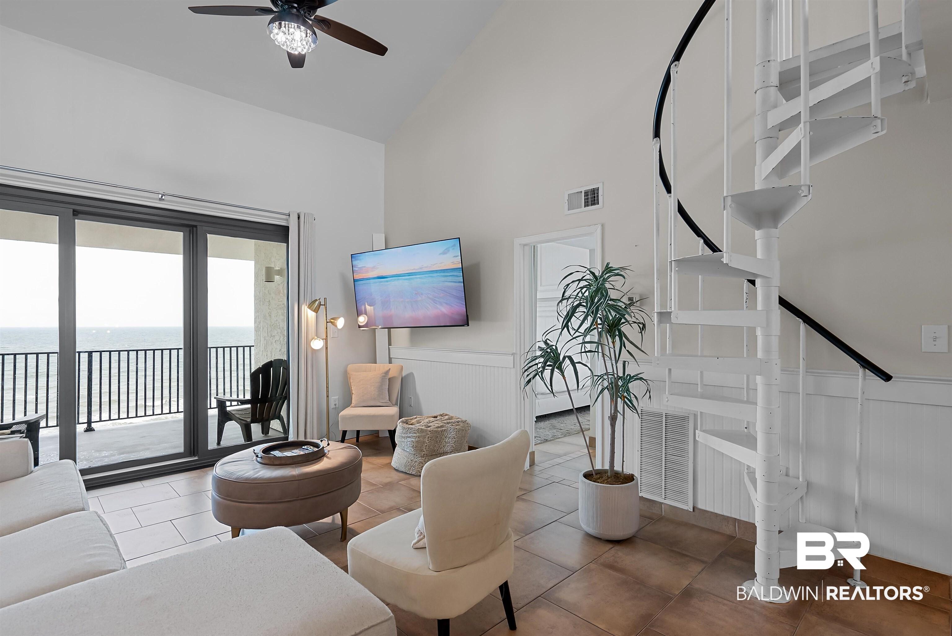 Image 3: Living area featuring a spiral staircase, vaulted ceilings, and tile flooring