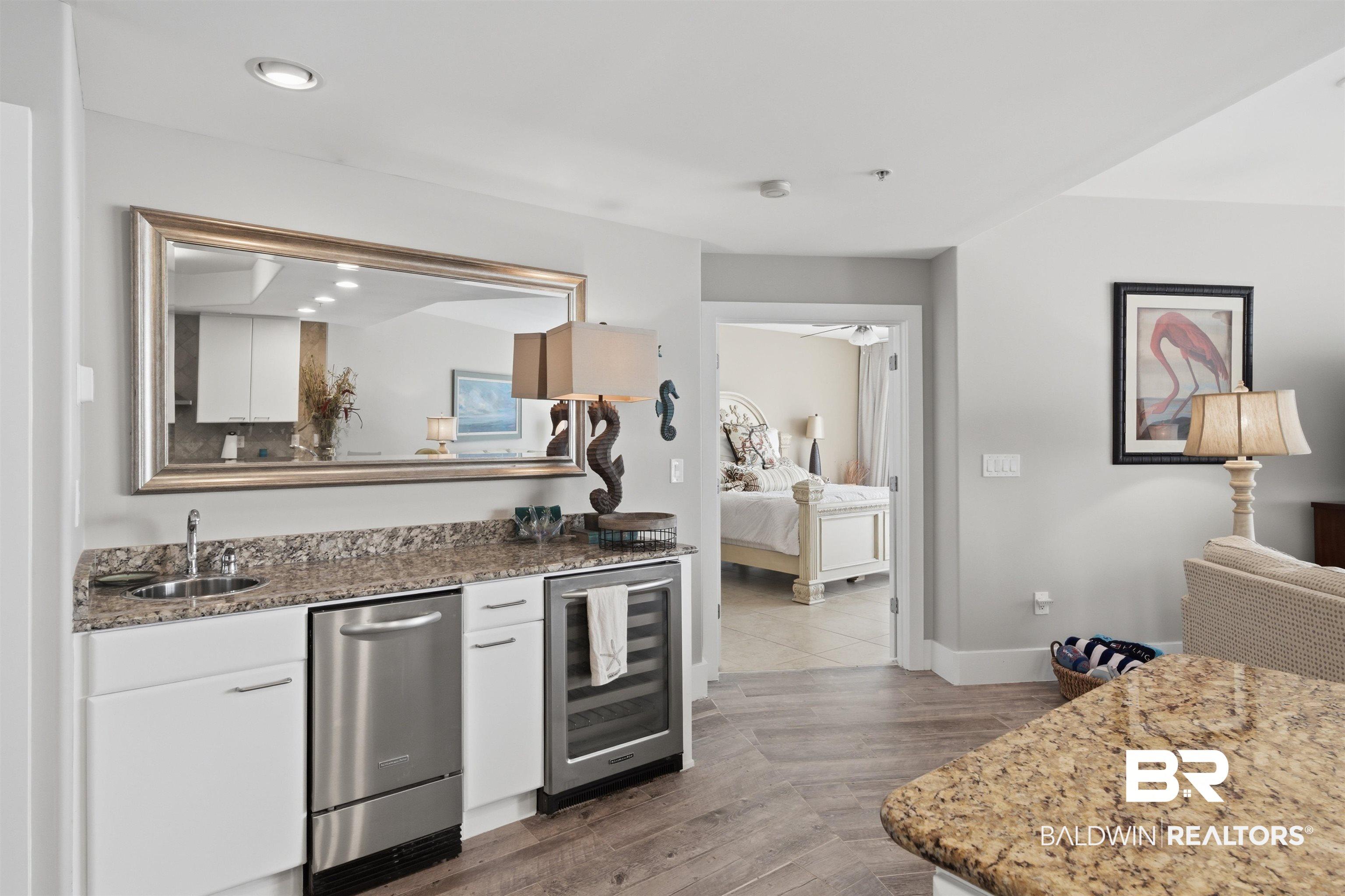 Image 4: Wet bar featuring a stainless steel undercounter refrigerator, stainless steel ice maker, granite countertop, and wood-finish flooring