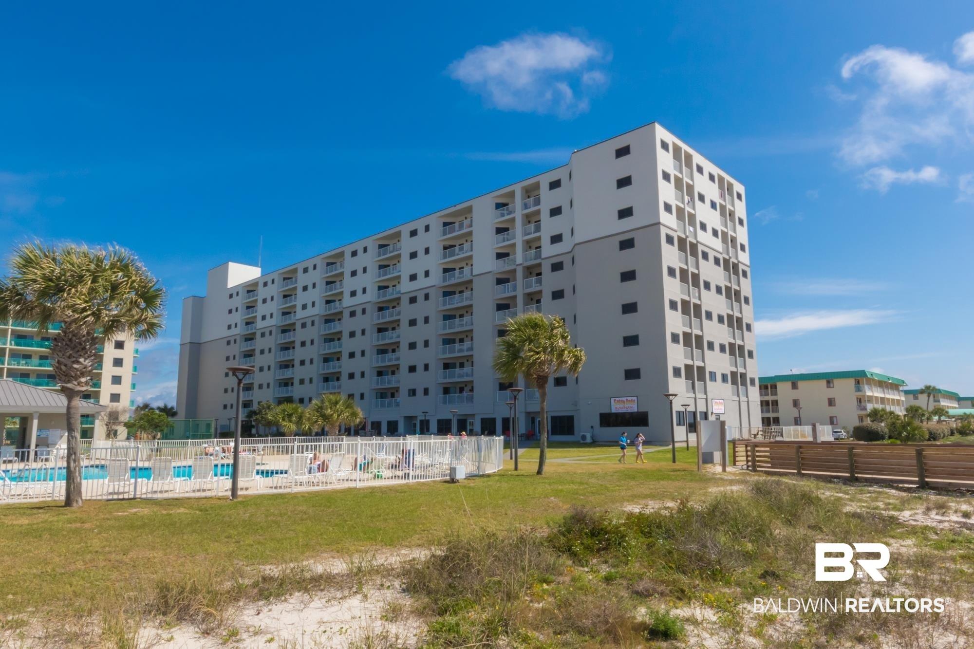 Image 1: Multi-story residential building featuring private balconies, an outdoor swimming pool, and a white perimeter fence