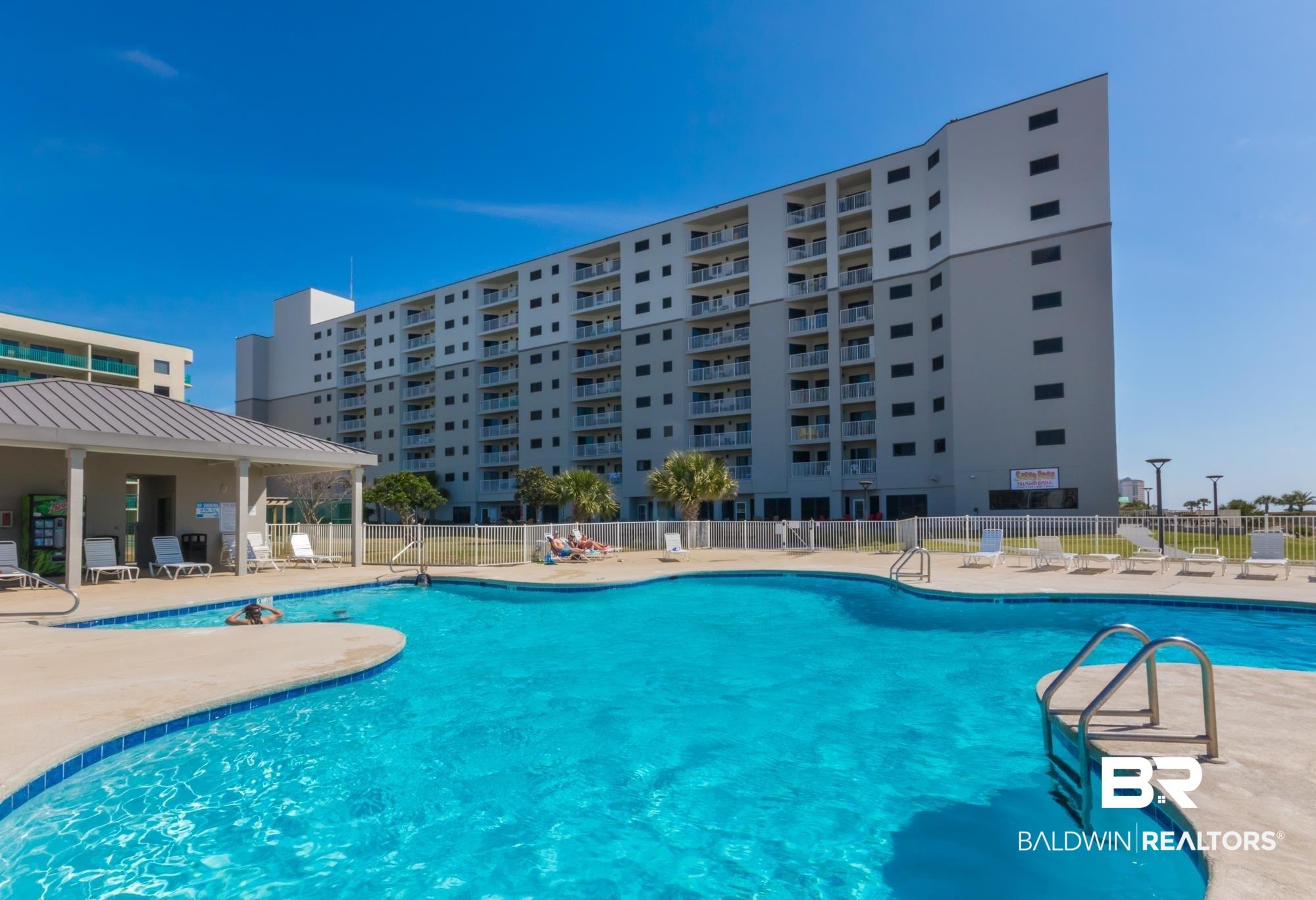 Image 2: Resort-style swimming pool with integrated seating, surrounded by a concrete deck with lounge chairs