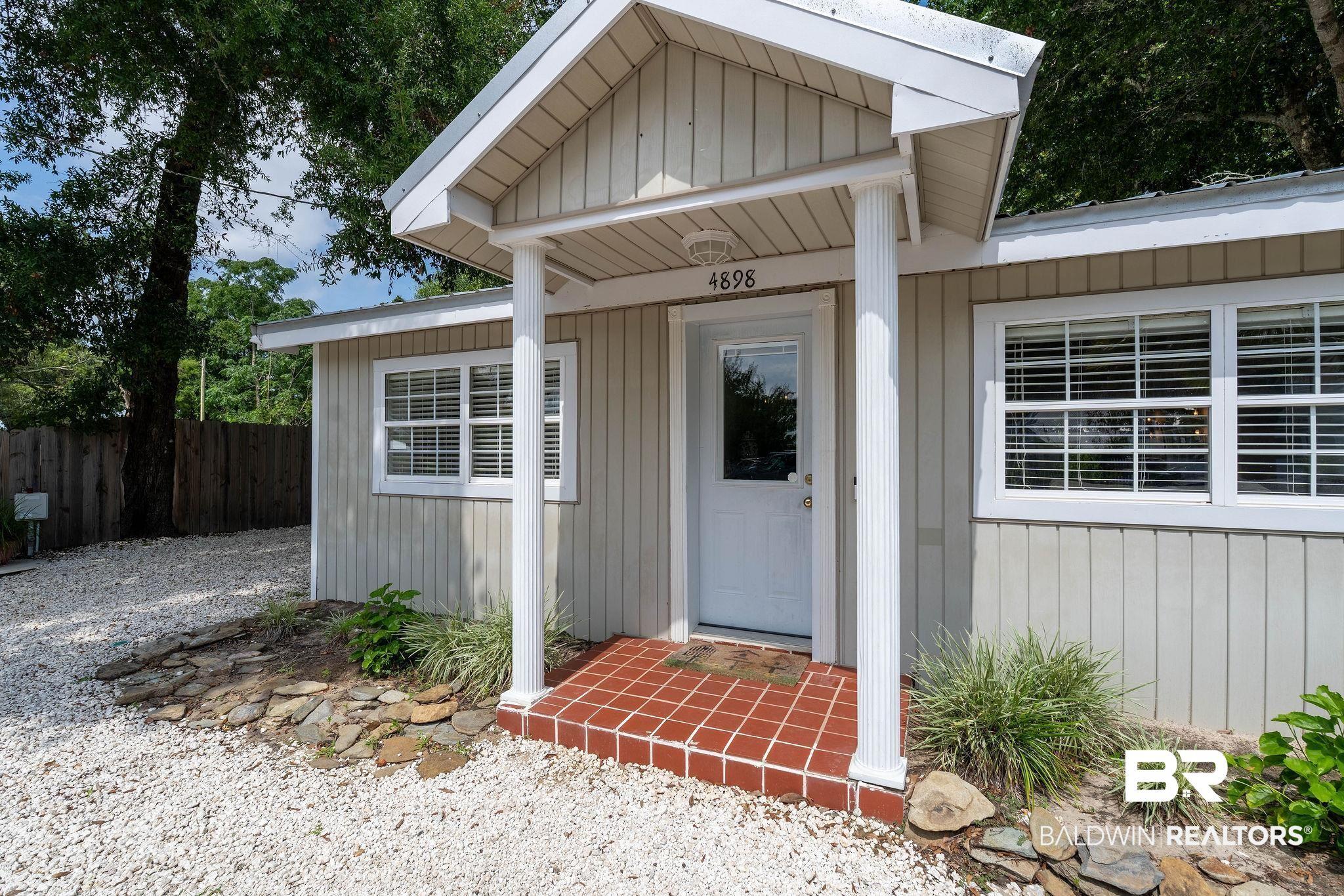 Image 1: Entryway featuring a covered porch with white columns, red tile flooring, and a glass-paneled door