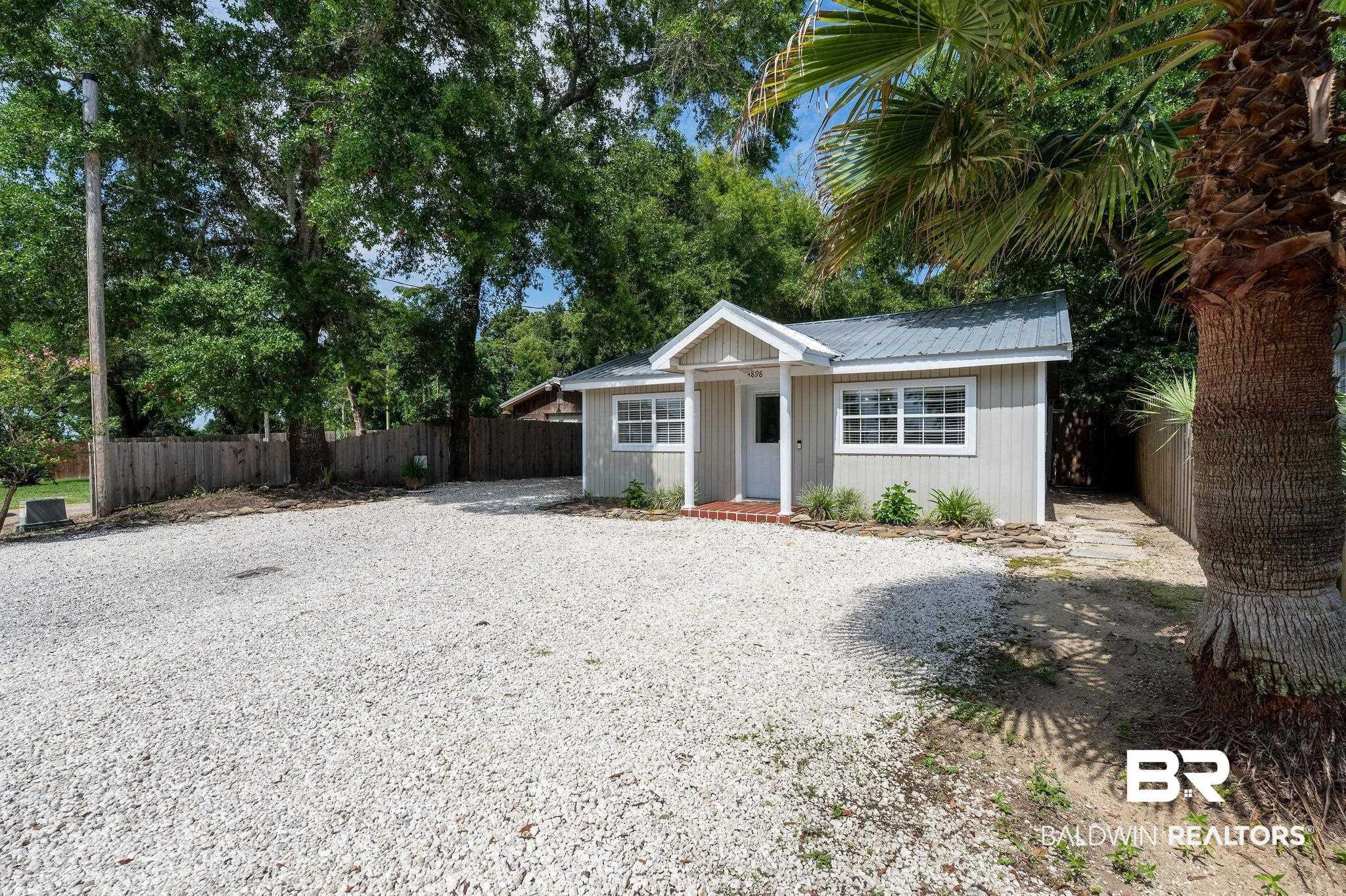 Image 4: Compact exterior featuring a light-colored siding, white-framed windows, and a metal roof