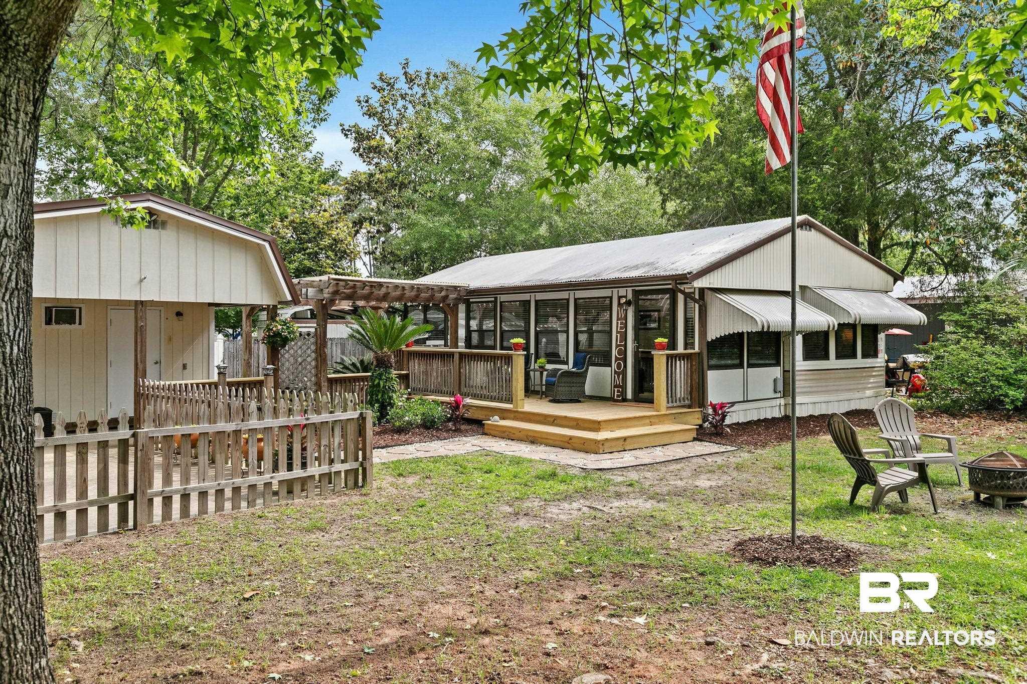 Image 1: Exterior featuring a screened porch with a wood deck, a detached storage building, a wood pergola, multiple awnings, and an expansive yard