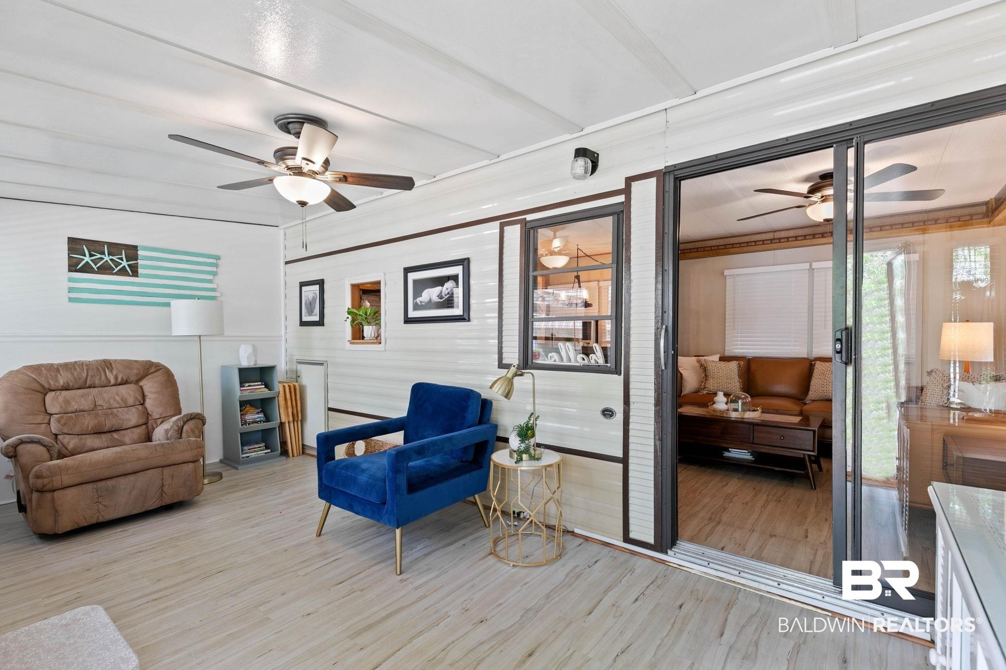 Image 2: Enclosed patio with light wood-finish flooring, white paneling, and two ceiling fans with integrated lighting