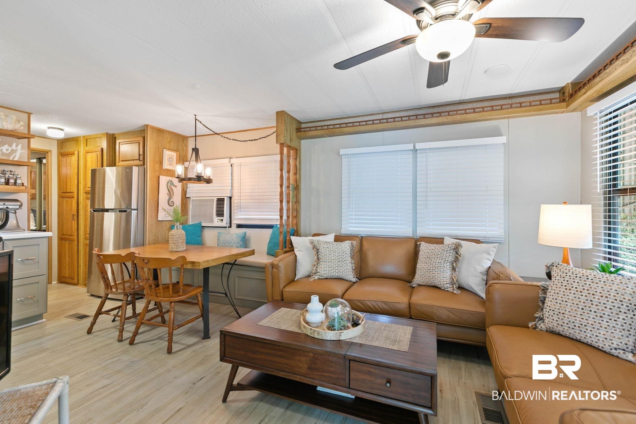 Image 4: Open-concept living area featuring light wood-finish flooring, a built-in window bench, white window blinds, and a ceiling fan with integrated lighting