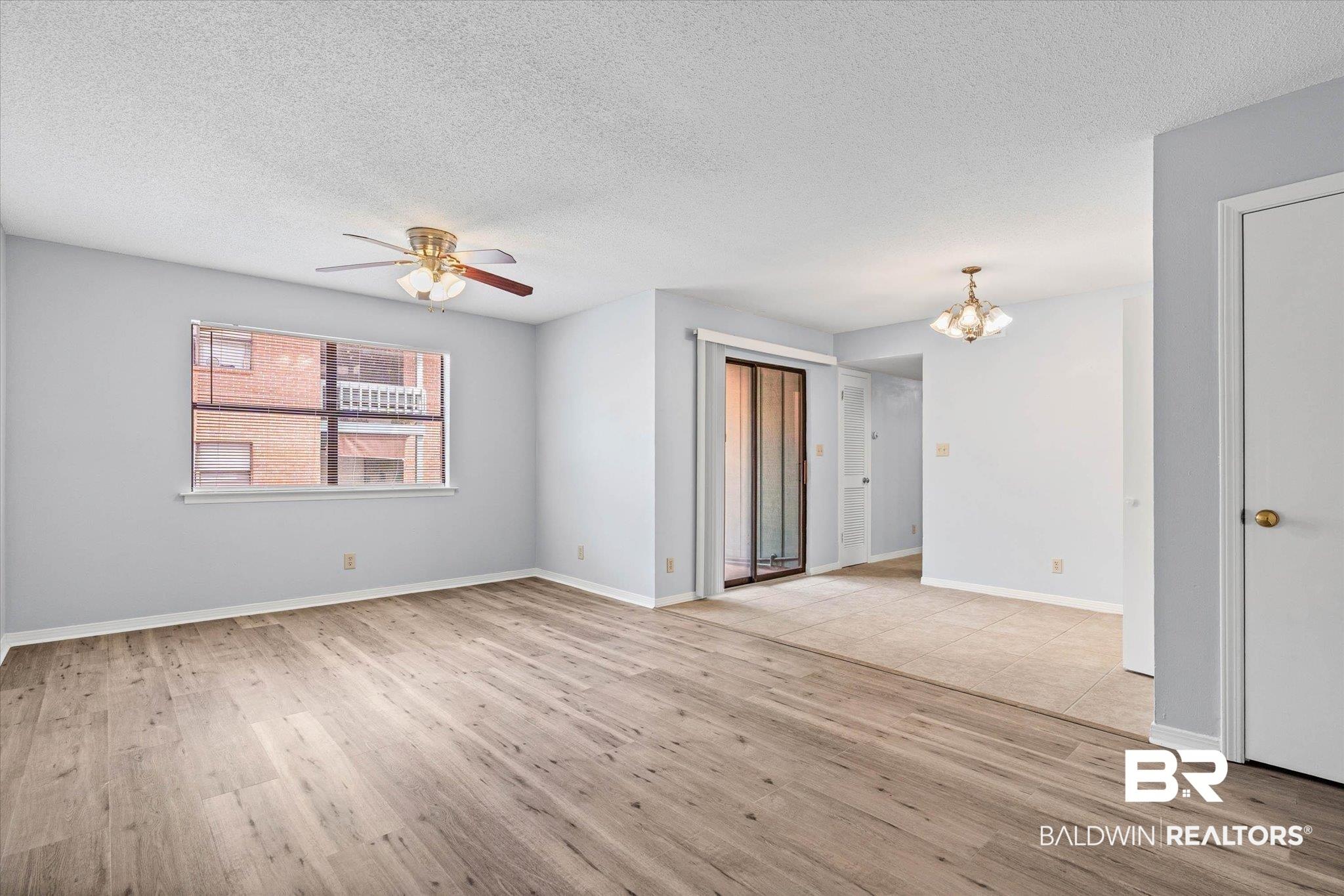 Image 3: Spacious room featuring wood-finish flooring, light gray walls, and a ceiling fan with integrated lighting