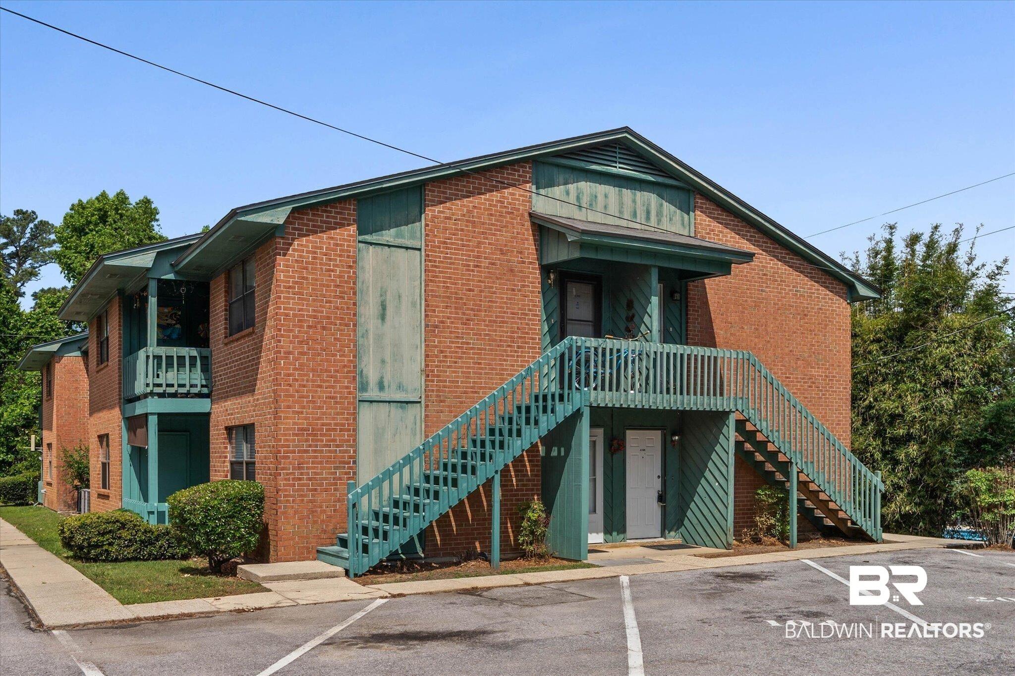 Image 1: Brick exterior building featuring a multi-story design, dual exterior staircases, individual entry doors, and a covered second-story balcony