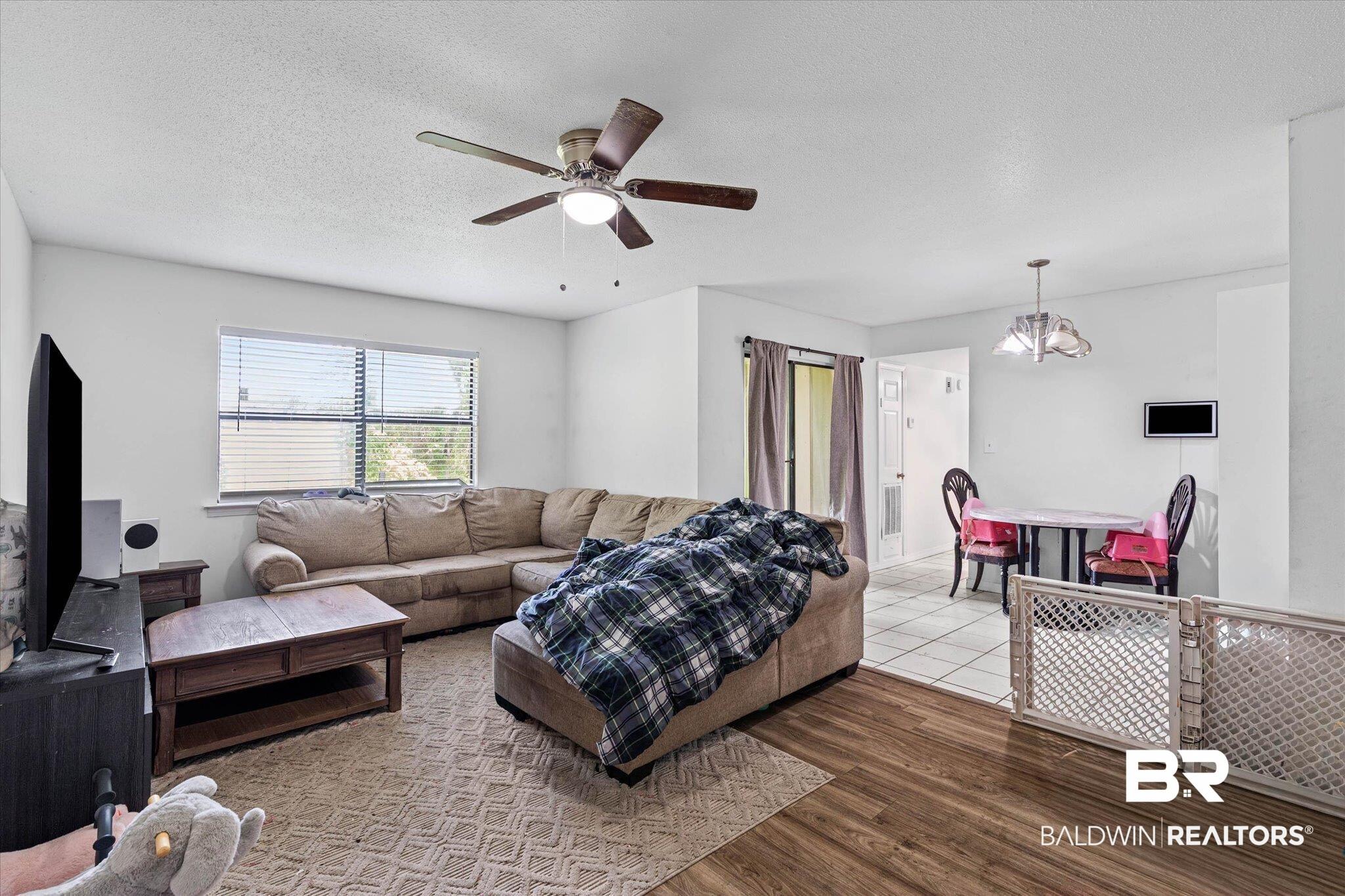 Image 3: Open-concept living space featuring wood-finish flooring extending into the living area and tile flooring in the dining area
