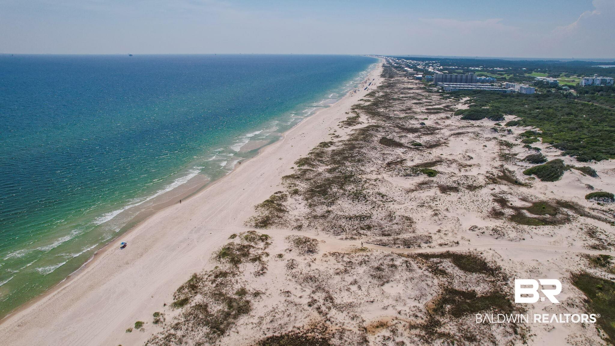 Image 3: Expansive beachfront property featuring white sand, clear turquoise waters, natural dunes, and dense coastal vegetation