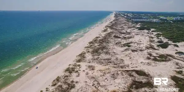 Image 3: Expansive beachfront property featuring white sand, clear turquoise waters, natural dunes, and dense coastal vegetation