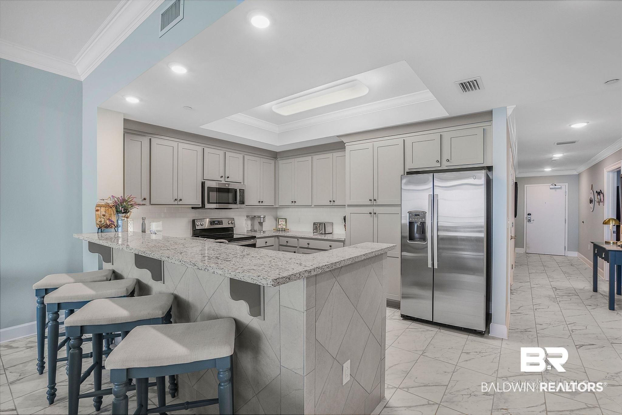 Image 3: Kitchen featuring light gray cabinetry, stainless steel appliances, a white subway tile backsplash, and granite countertops