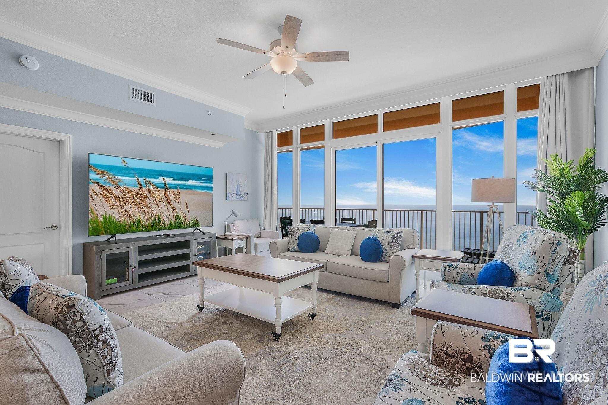 Image 4: Spacious living area featuring floor-to-ceiling windows, crown molding, a ceiling fan, and light-colored flooring