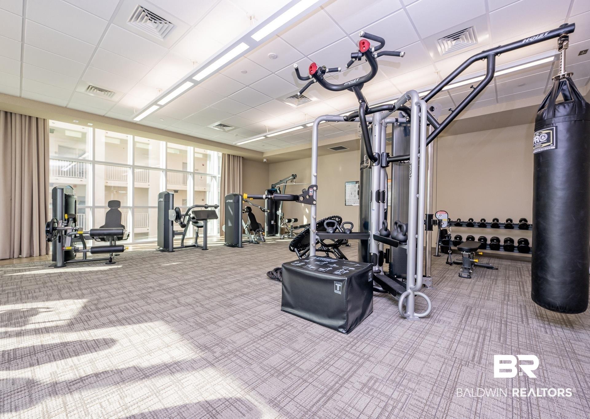 Image 3: Fitness center featuring a variety of exercise equipment, a punching bag, and a full set of dumbbells