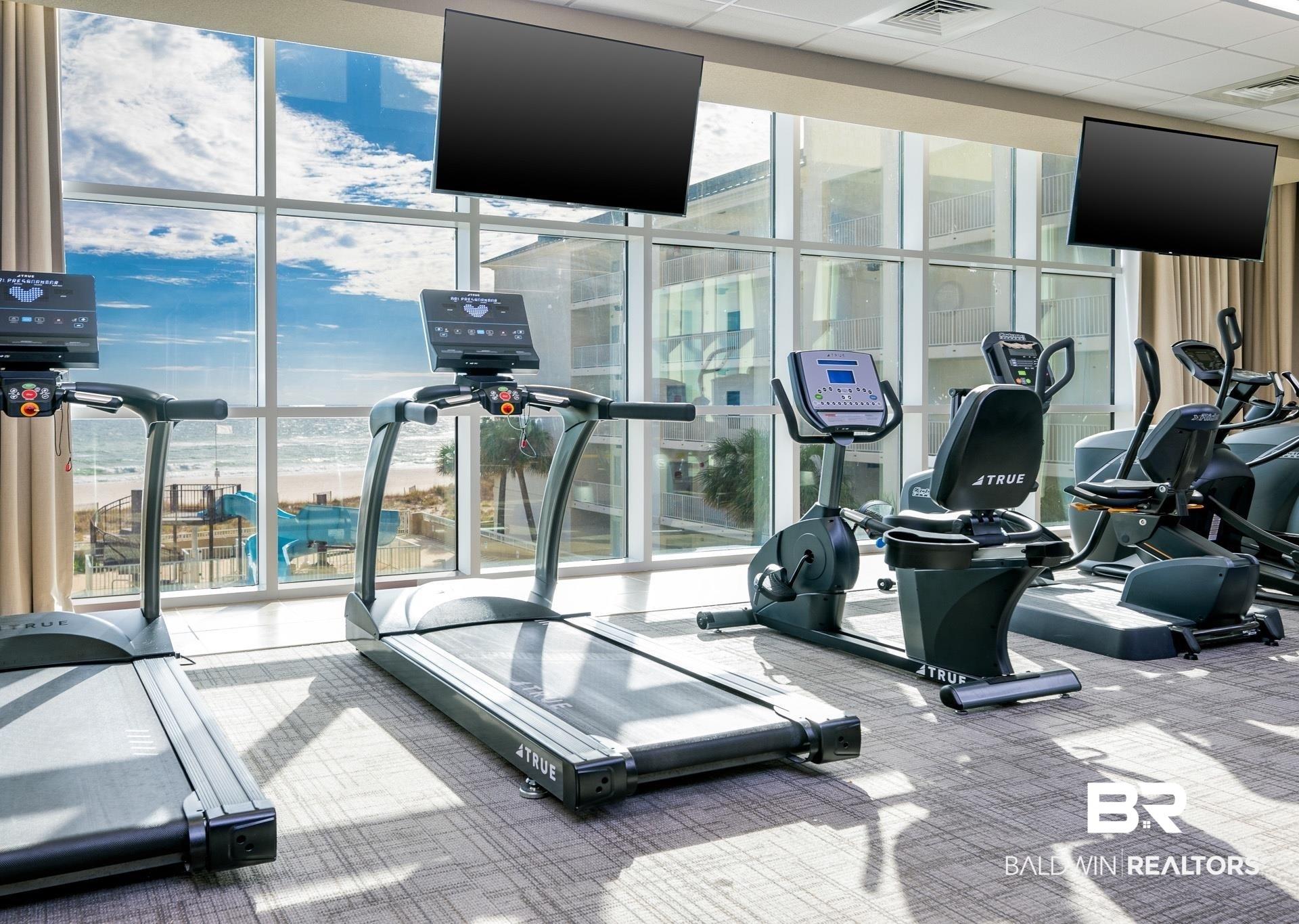 Image 4: Fitness area featuring floor-to-ceiling windows, multiple wall-mounted televisions, and carpeting