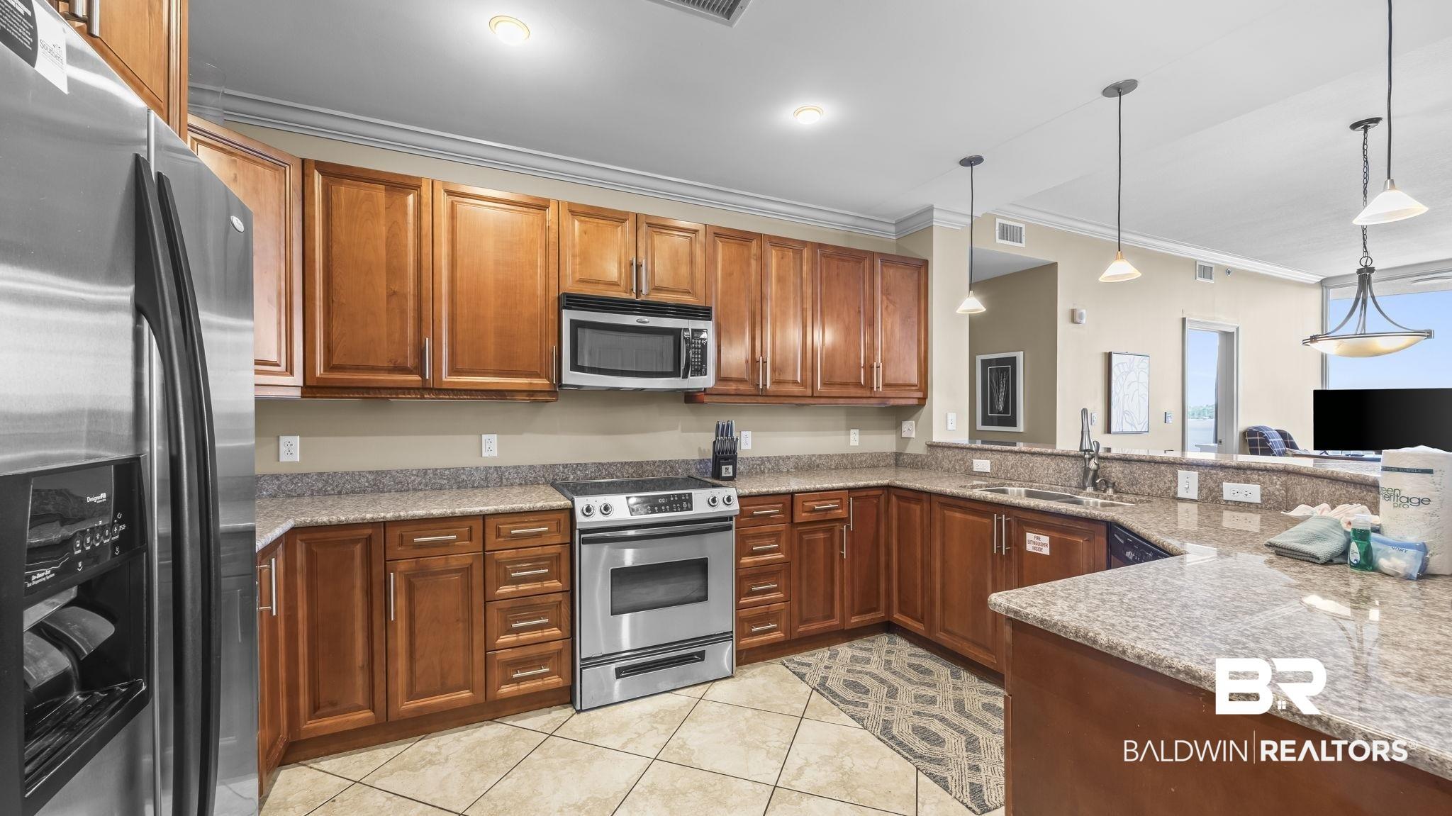 Image 3: Kitchen featuring wood cabinetry, stainless steel appliances, granite countertops, and tile flooring