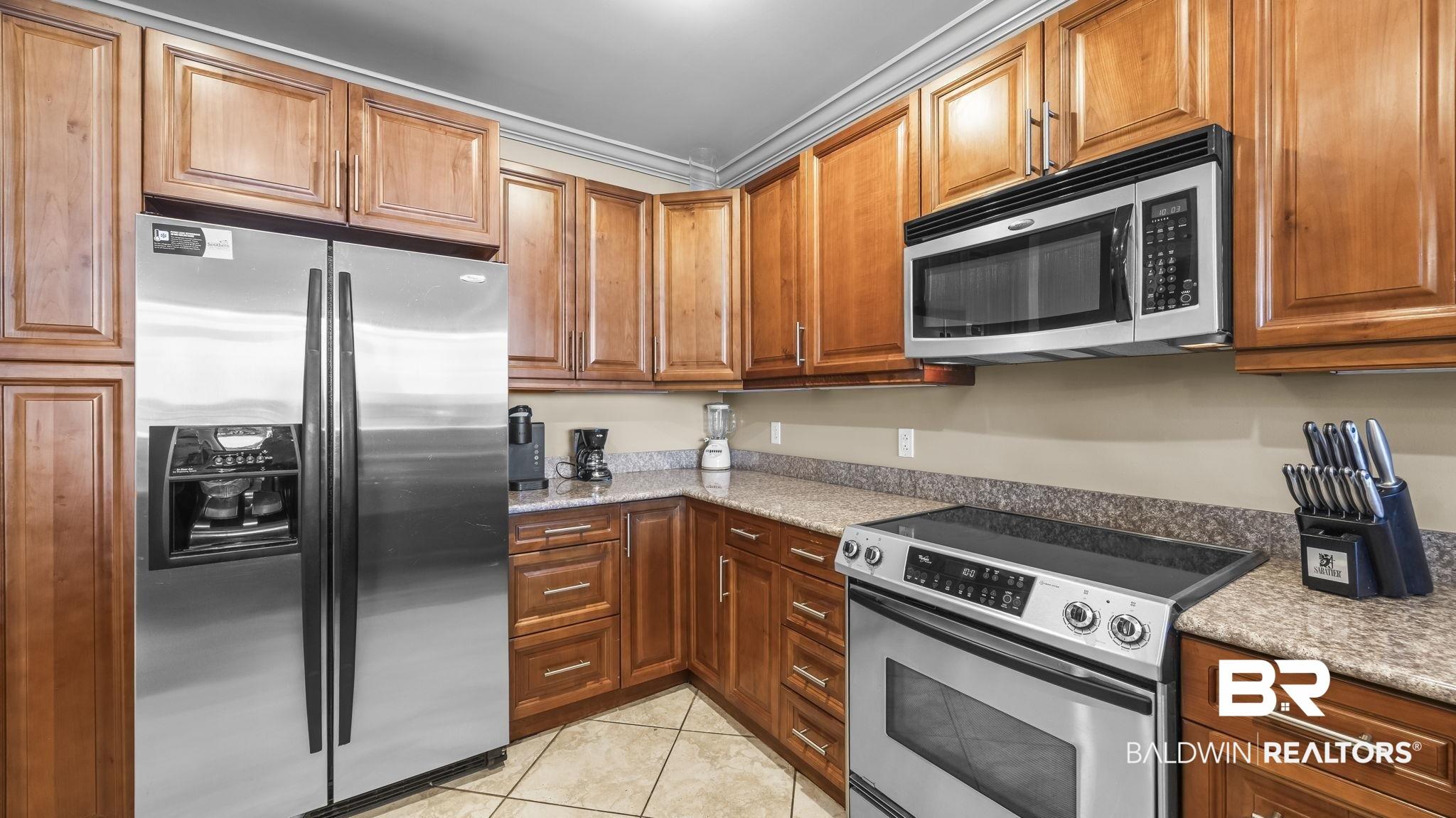 Image 4: Kitchen featuring abundant wood cabinetry, stone-look countertops, and tile flooring